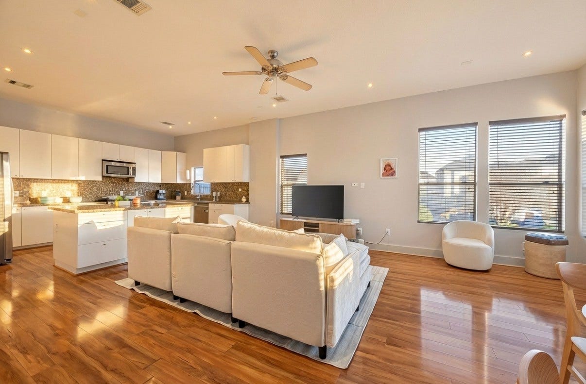5111 Cornish Street, Houston, TX 77007 Spacious open-concept living area with warm wood flooring, modern kitchen cabinetry, and large windows offering ample natural light.