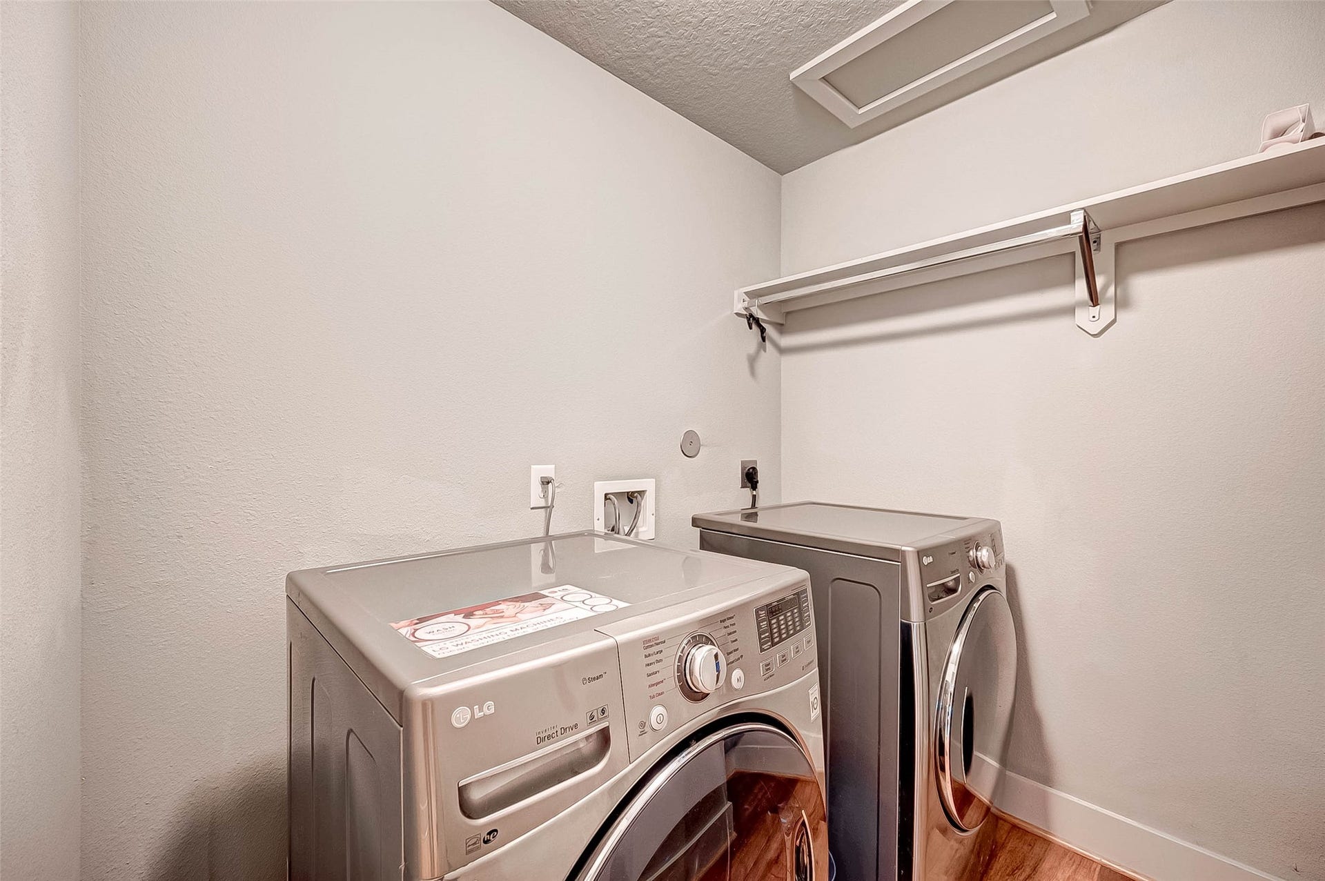 5111 Cornish Street, Houston, TX 77007 Modern laundry room with sleek LG washer and dryer, wood flooring, and a convenient overhead shelf for storage.