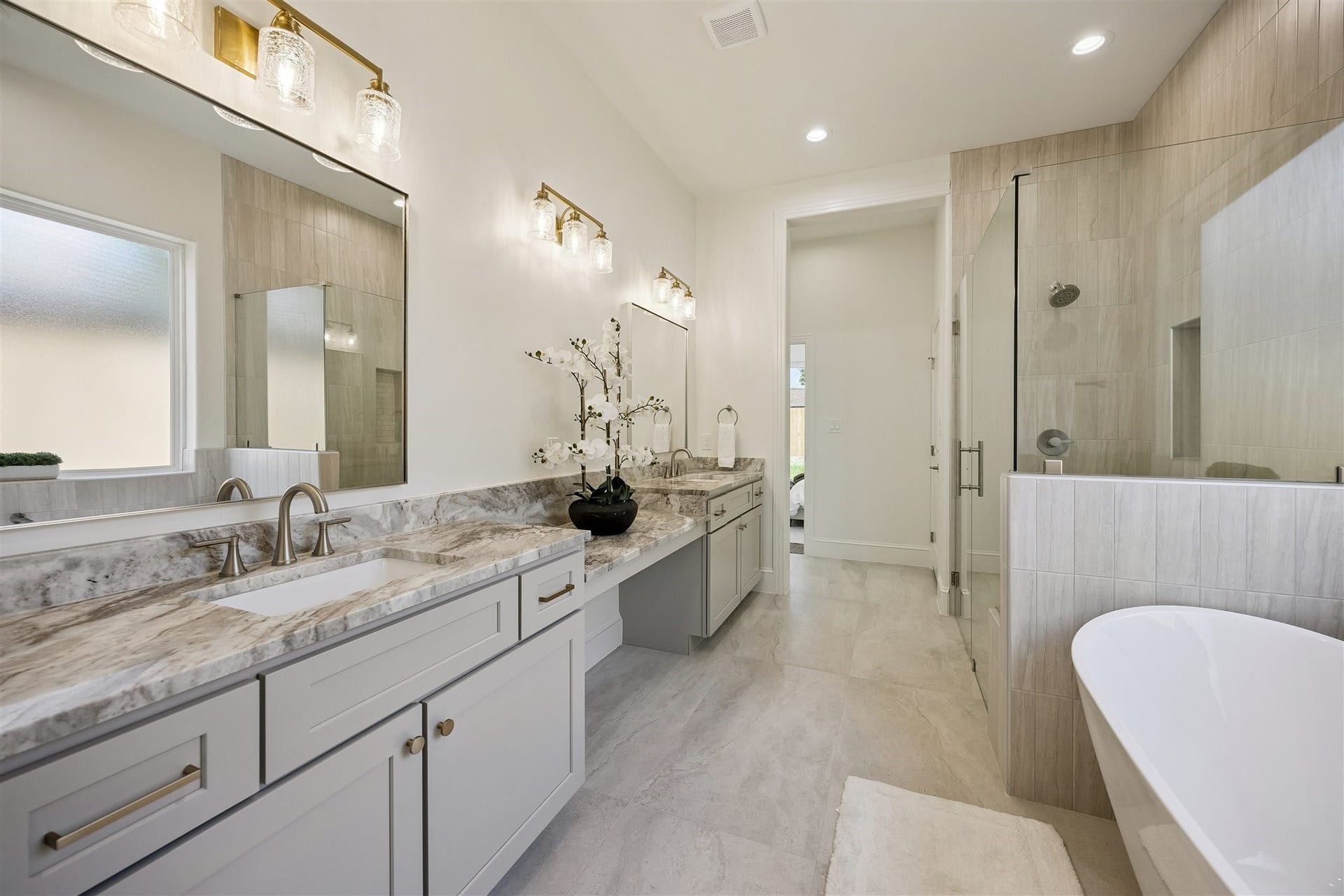 Primary bathroom with double sinks, vanity area, and separate shower and soaking tub