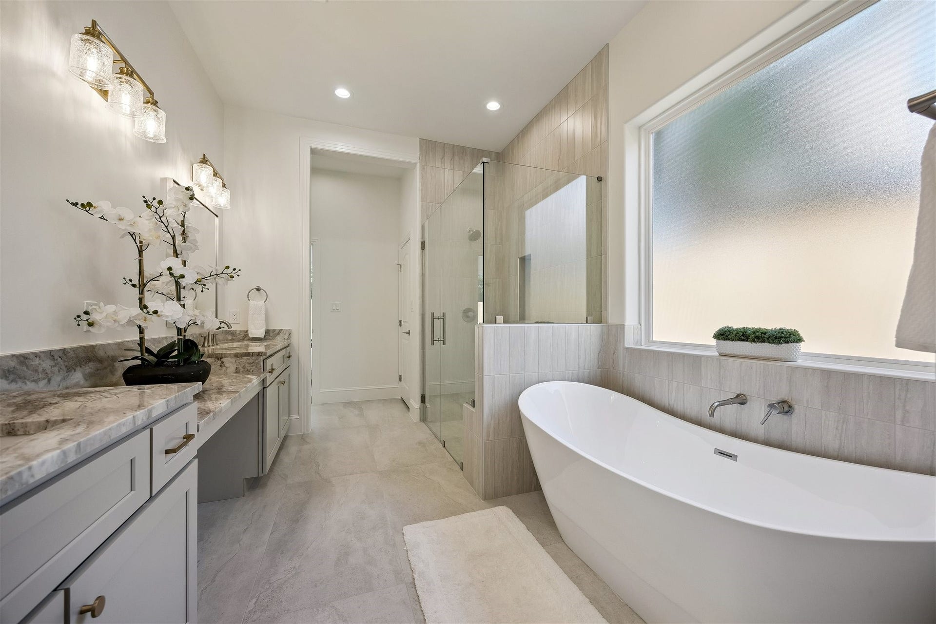 Primary bathroom with double sinks, vanity area, and separate shower and soaking tub