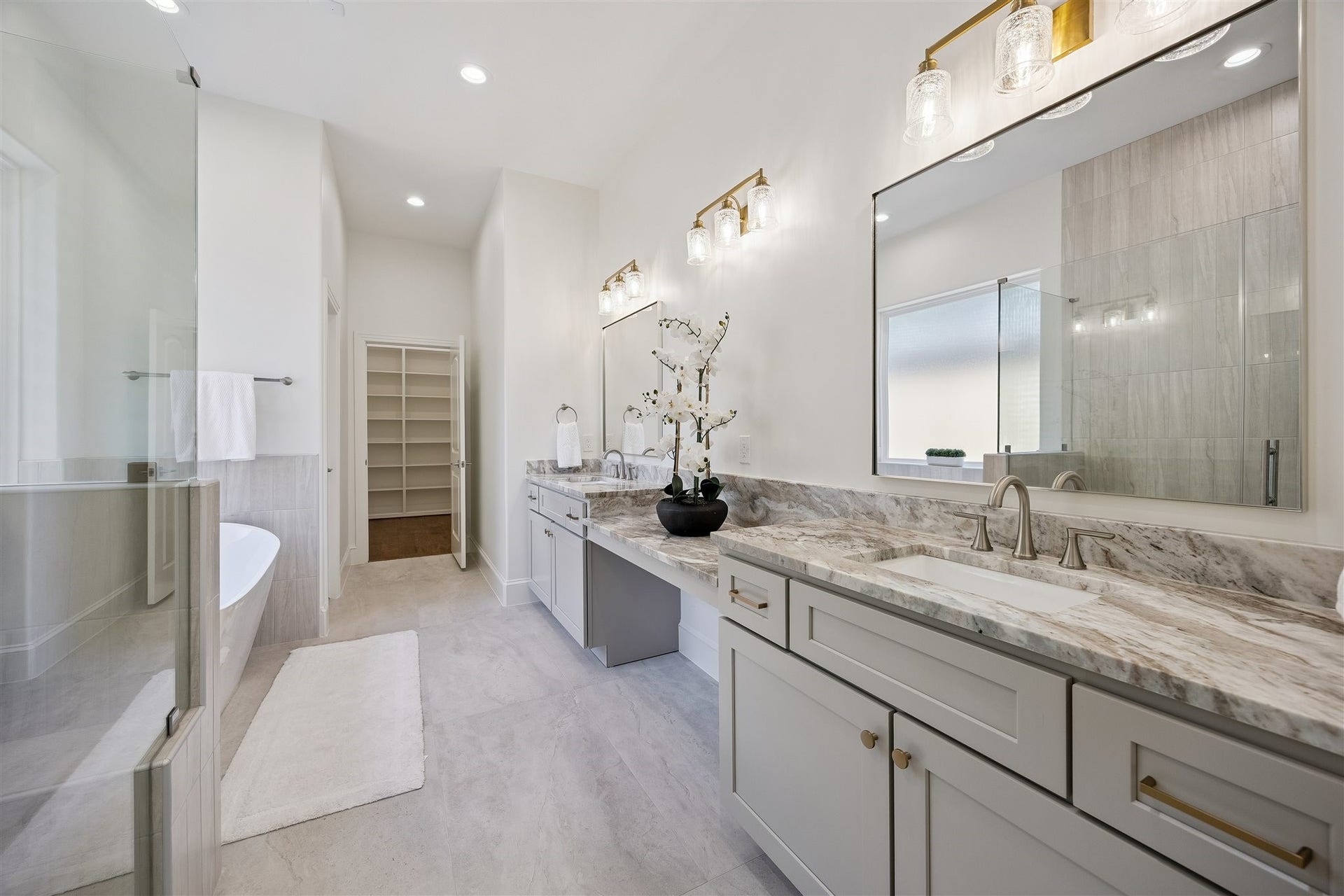 Primary bathroom with double sinks, vanity area, and separate shower and soaking tub