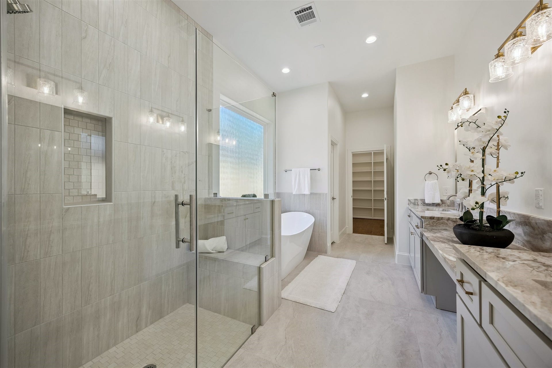 Primary bathroom with double sinks, vanity area, and separate shower and soaking tub