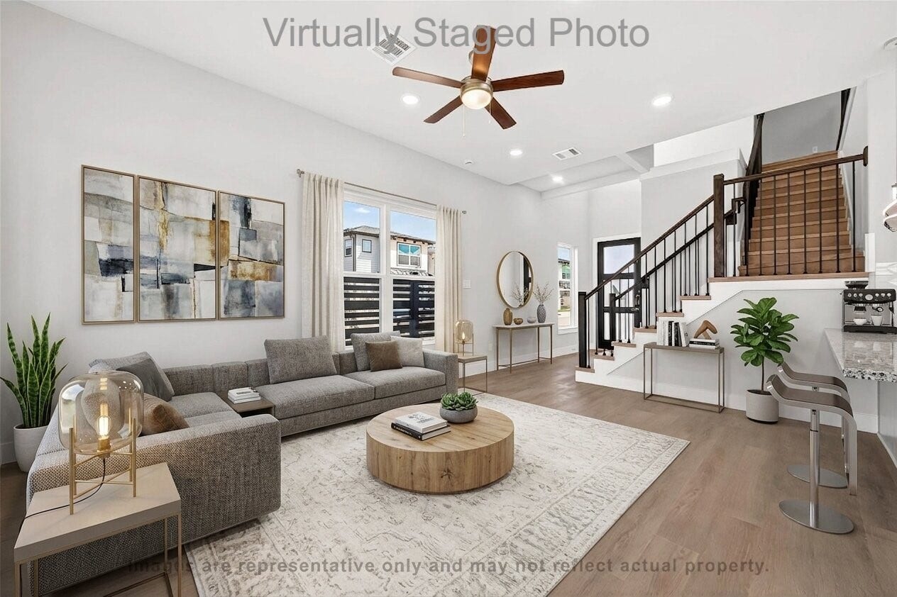 10719 Mason Rd, #32, Richmond, TX 77406 Virtual Staging - Modern living room featuring a large gray sectional sofa, a round wooden coffee table, and an adjacent open staircase