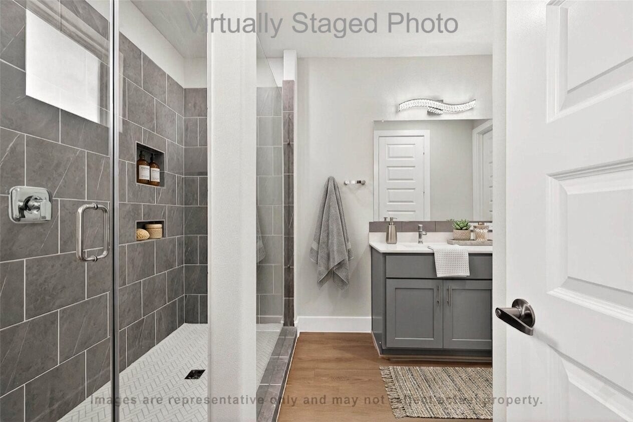 10719 Mason Rd, #32, Richmond, TX 77406 Virtual Staging - This is a modern bathroom featuring a glass-enclosed walk-in shower with grey tile, a sleek grey vanity, and light wood-style flooring