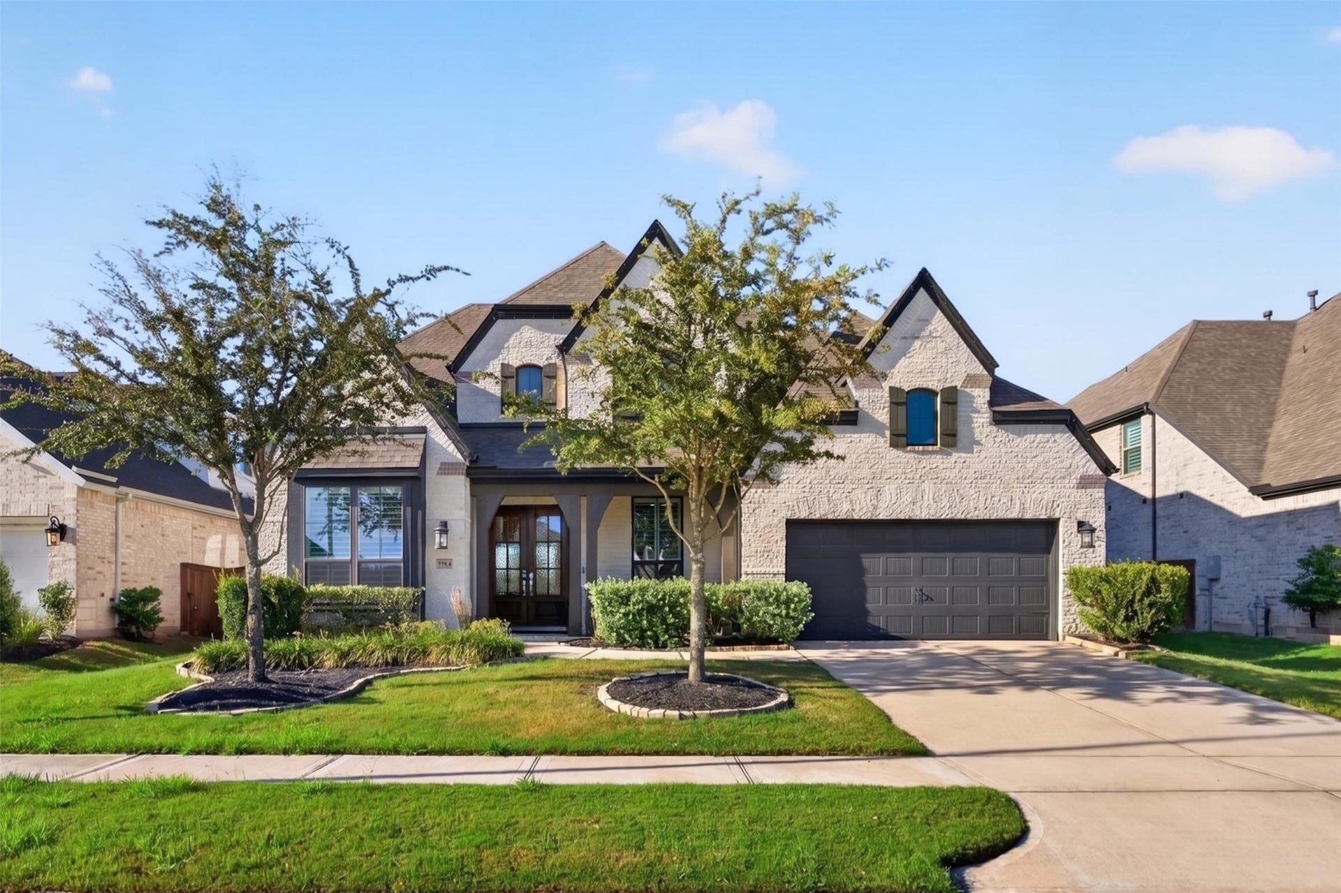 7014 San Bernard Trail, Katy, TX 77493 Charming two-story home with a stone facade and elegant gabled roofline, featuring a spacious double garage and well-maintained front yard and lush landscaping.