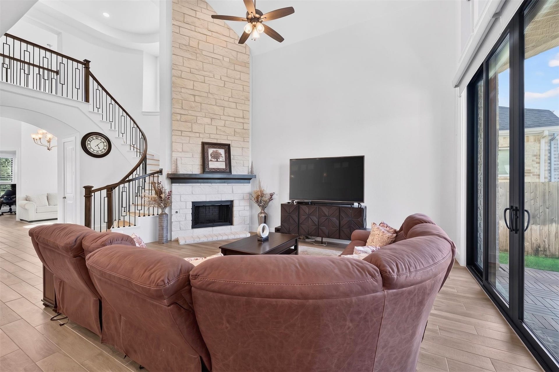 7014 San Bernard Trail, Katy, TX 77493 Spacious living room with high ceilings, a cozy stone fireplace, and abundant natural light from large windows.
