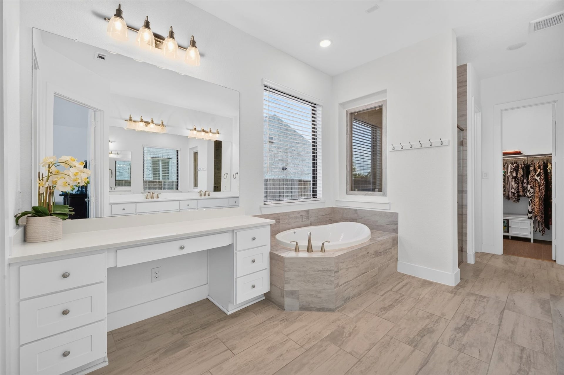 7014 San Bernard Trail, Katy, TX 77493 Elegant bathroom featuring a luxurious soaking tub, spacious vanity with ample storage, and modern lighting, all complemented by large windows for natural light.