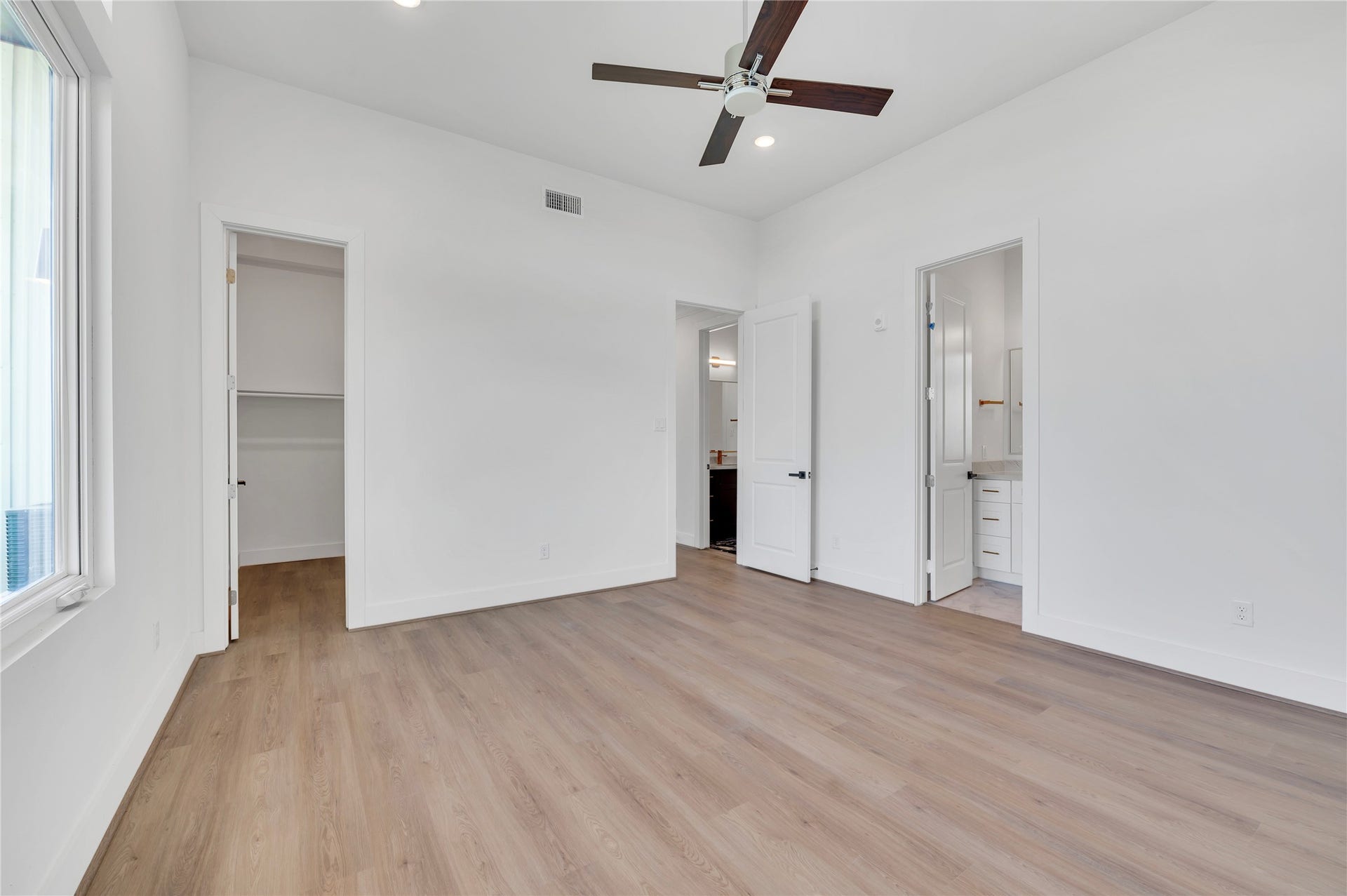 119 Kirby Road, #5303, Taylor Lake Village, TX 77586 Bright and spacious bedroom featuring sleek hardwood floors, a modern ceiling fan, and convenient access to a walk-in closet and en-suite bathroom.
