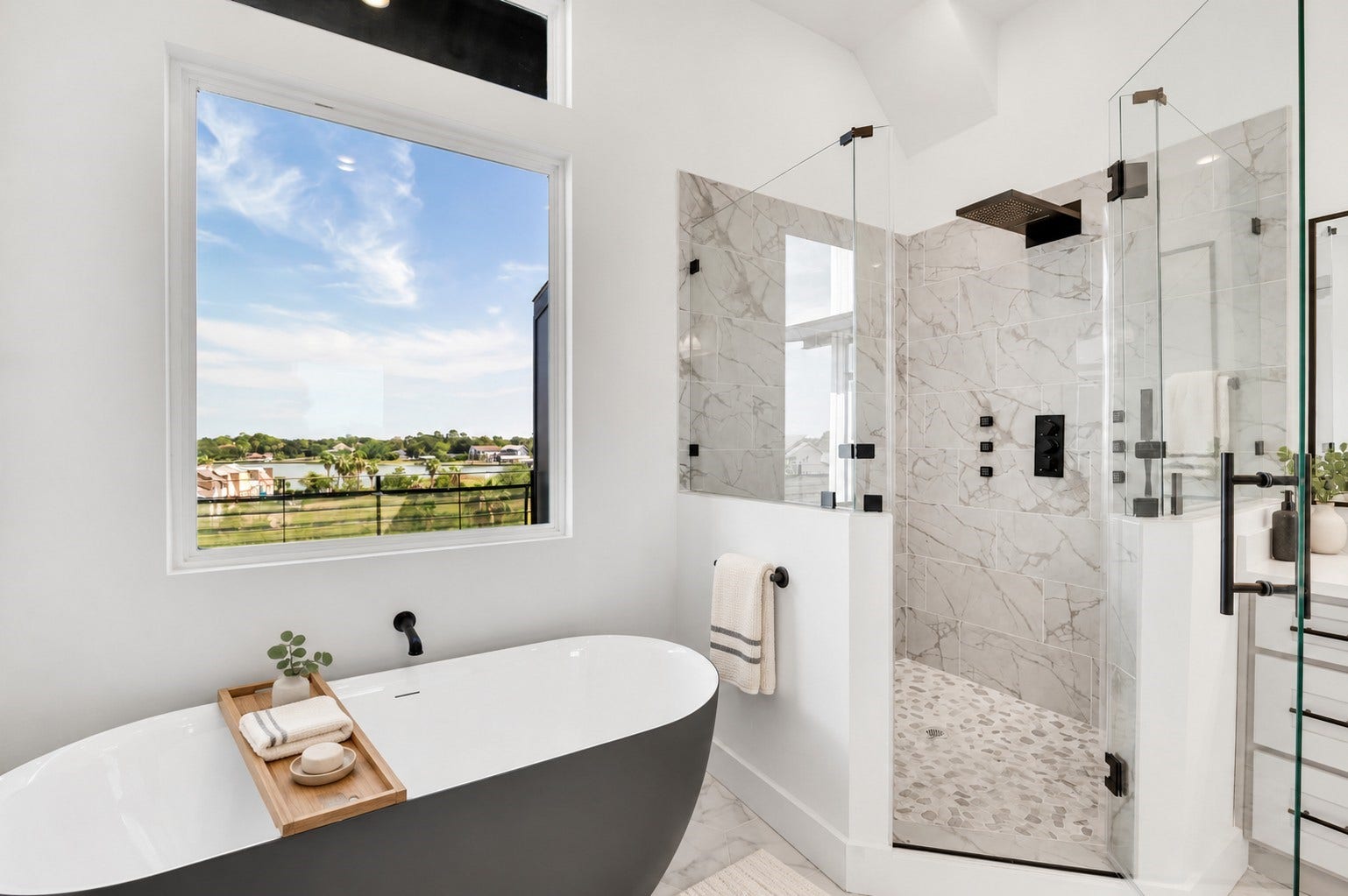 119 Kirby Road, #5303, Taylor Lake Village, TX 77586 Experience luxury in this elegant bathroom featuring a sleek freestanding tub, a spacious glass-enclosed shower with marble tiles, and a large window offering picturesque views.
