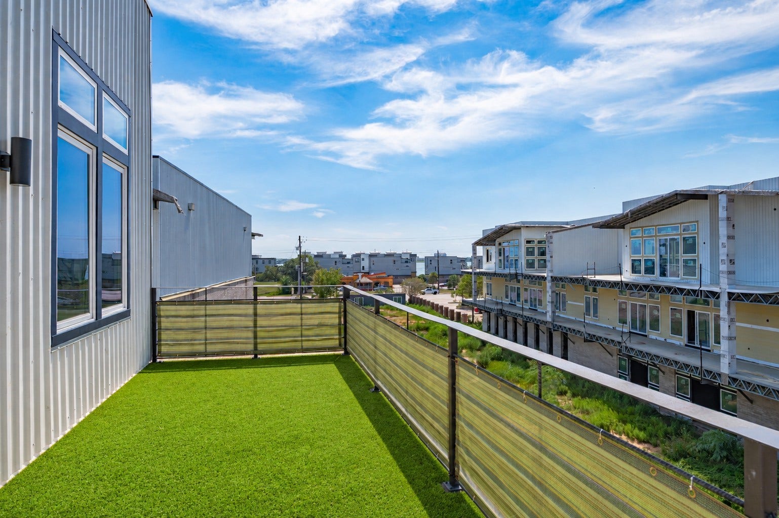 119 Kirby Road, #5303, Taylor Lake Village, TX 77586 Spacious rooftop terrace with artificial grass, offering expansive views of modern townhouses and a vibrant neighborhood.