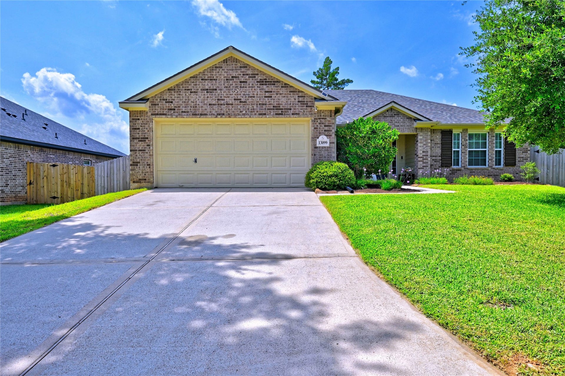13099 Greenbriar, Willis, TX 77318 Charming single-story brick home with a two-car garage and well-maintained front yard. The spacious driveway and lush landscaping enhance curb appeal, while a welcoming front porch adds to the home's inviting atmosphere.