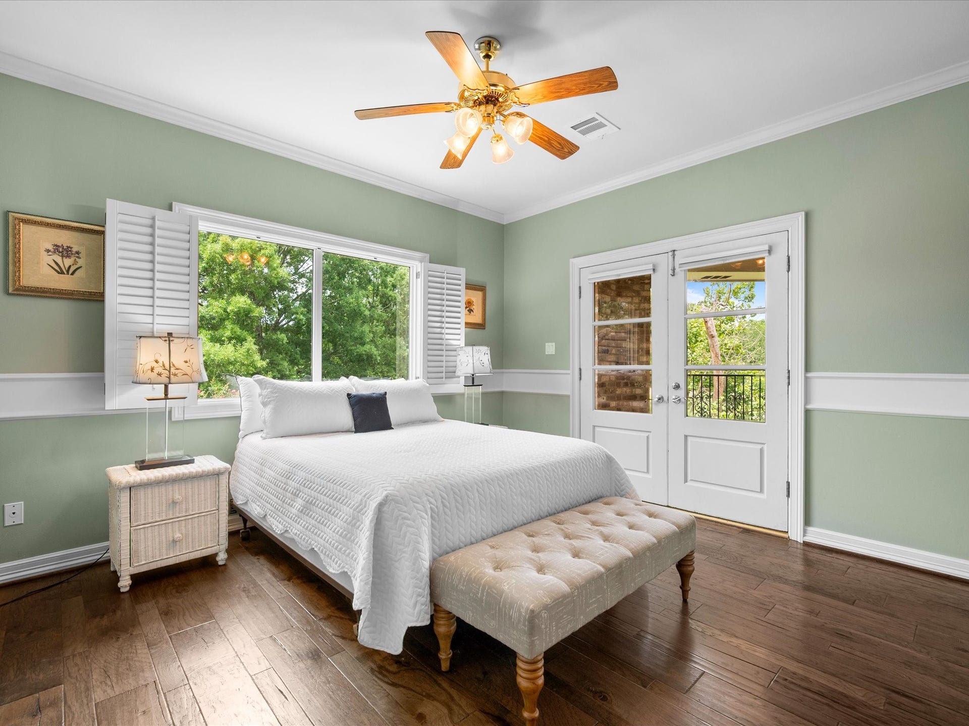 Expansive windows fill this spacious third bedroom with natural light, while crown molding and gleaming wood floors add warmth and timeless appeal.