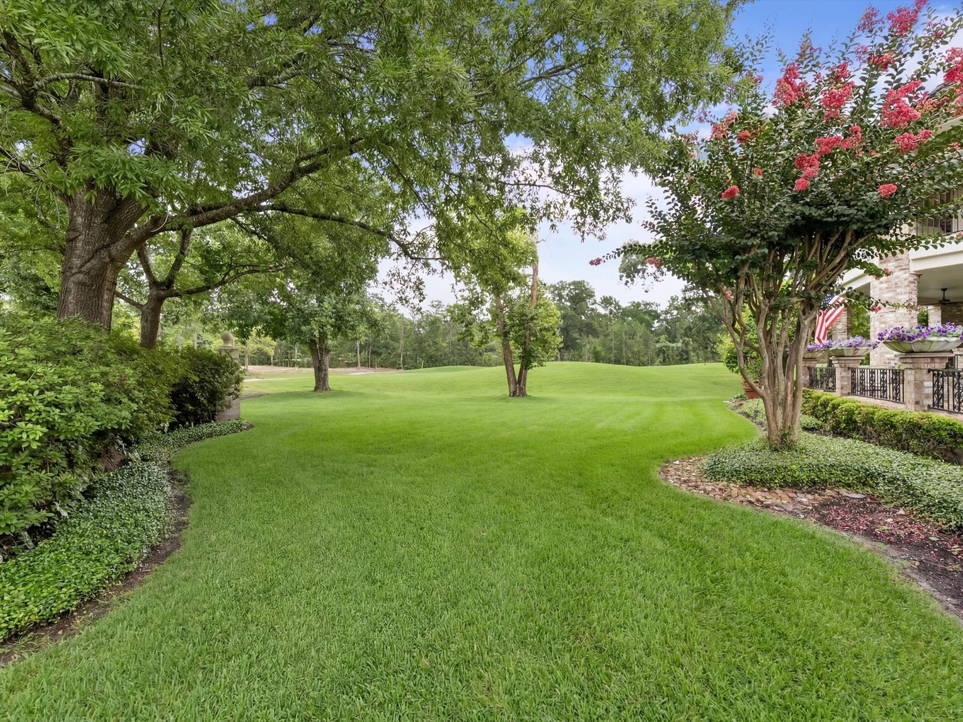 Beautiful mature trees, vibrant crepe myrtles, and meticulously manicured landscaping create a picturesque setting that enhances the home's timeless French Country charm.