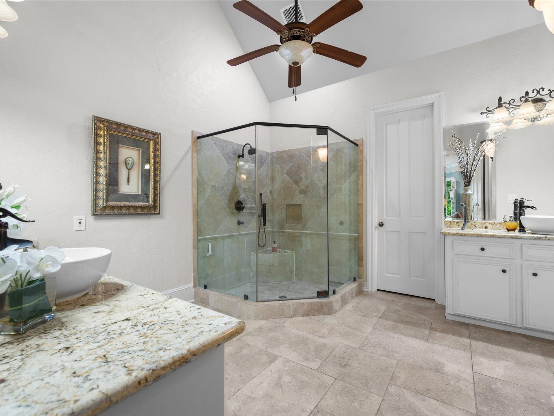 Designed to rival a luxury spa, the exquisite primary bath features a massive glass-enclosed shower, dual vessel sinks, dedicated vanity space, and an atmosphere of everyday indulgence.