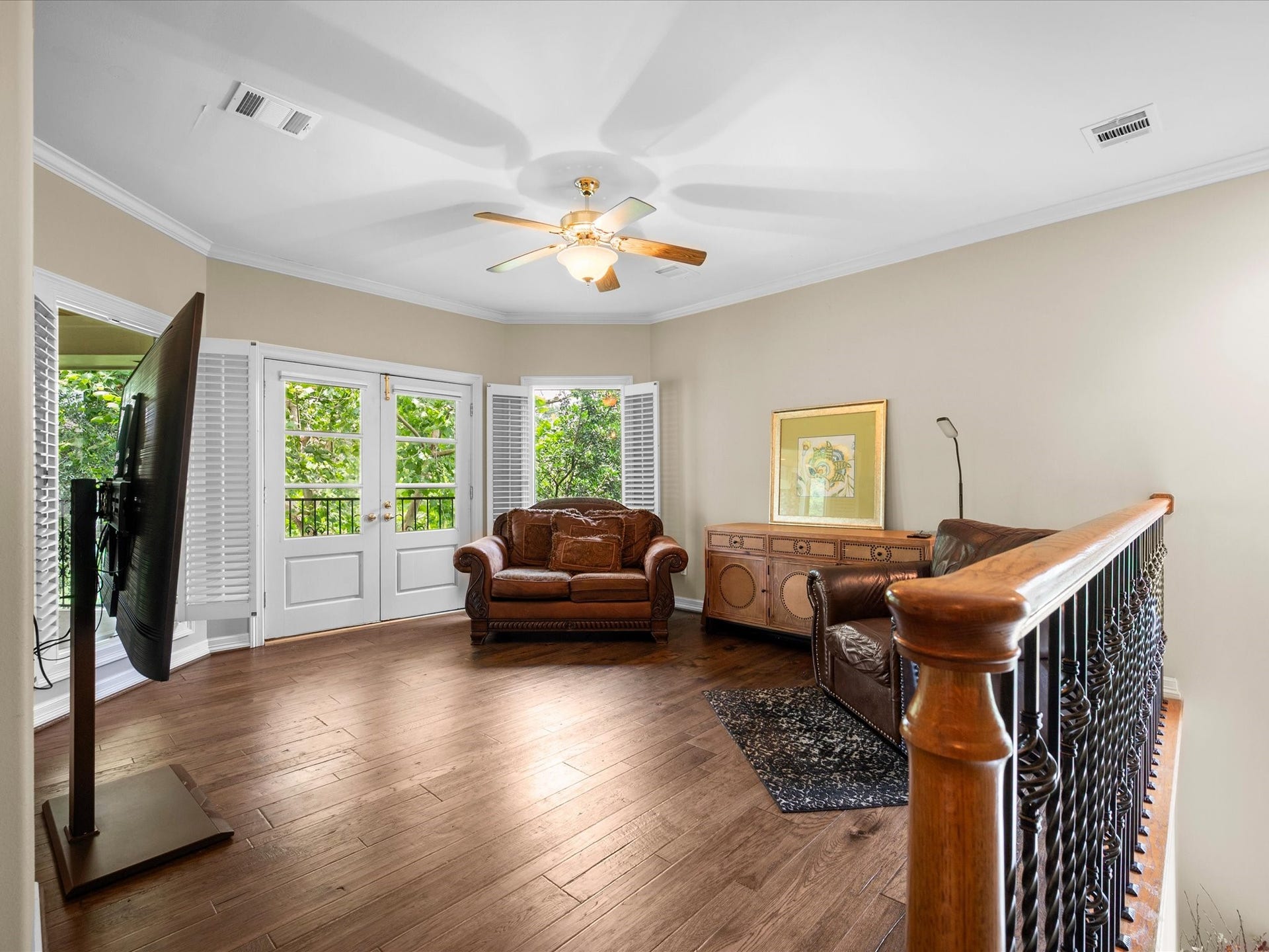 The spacious upstairs game room is filled with natural light from expansive windows and French doors that seamlessly extend the living space to the balcony beyond.