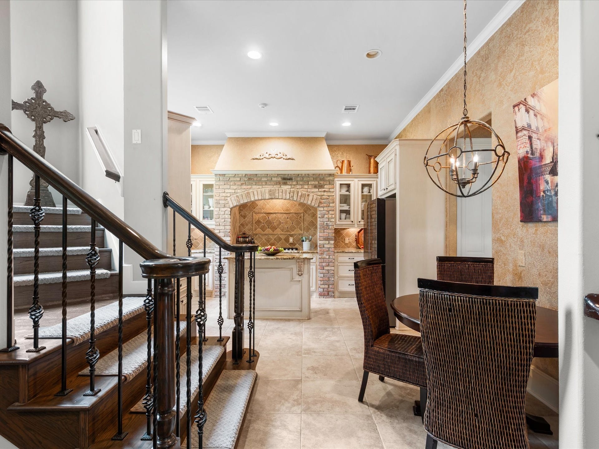 Rich wood and iron staircase details, elegant lighting, and a charming breakfast nook beautifully capture the timeless character and French Country charm found throughout the home.