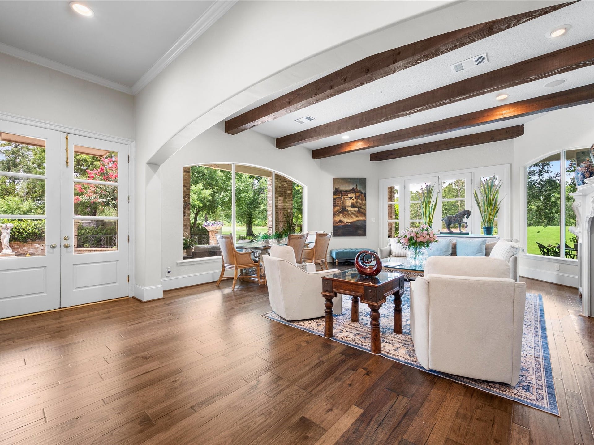Exposed beams and expansive windows fill the family room with natural light while showcasing the beauty of the surrounding landscape, creating a warm and inviting gathering space.