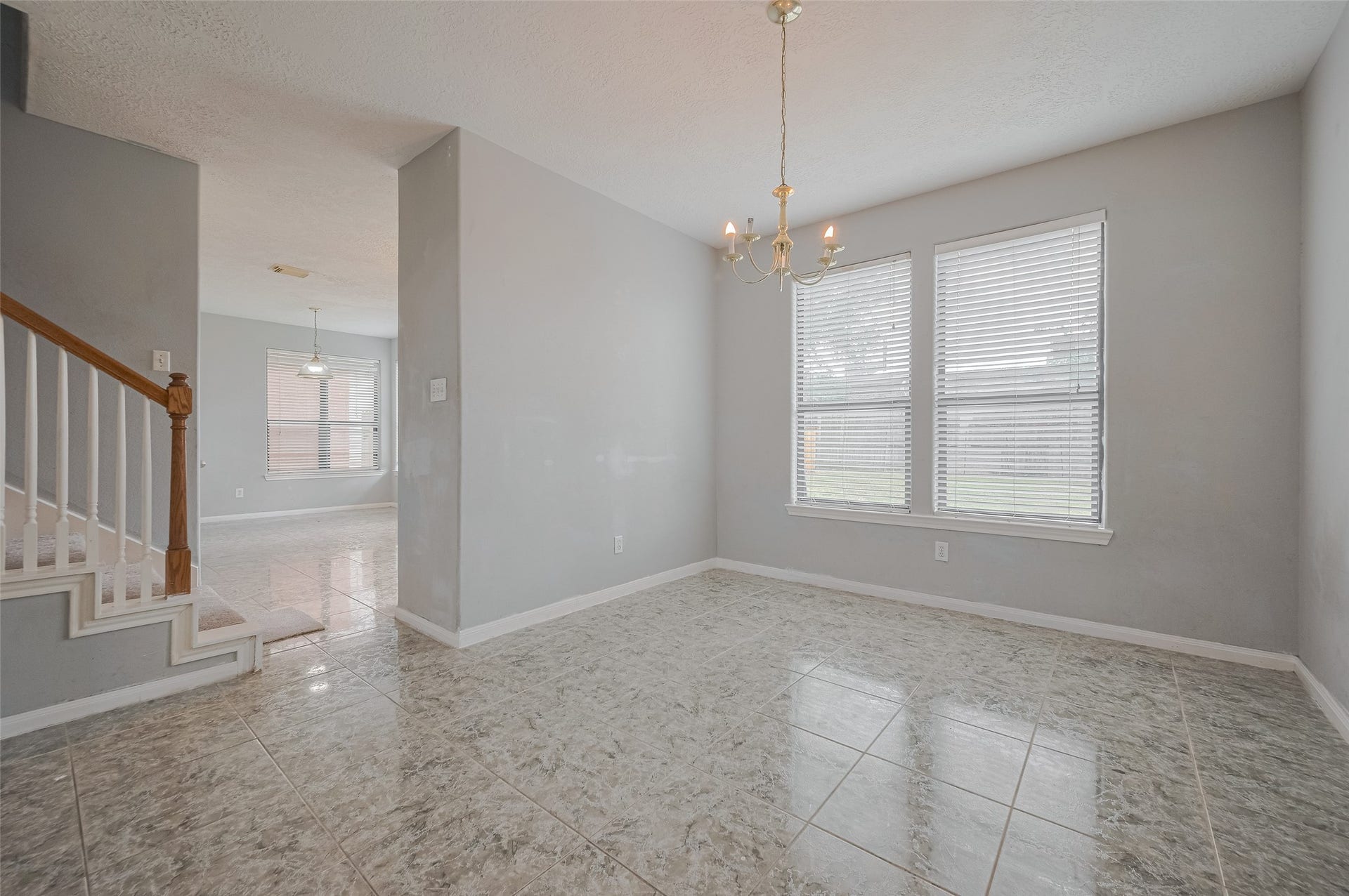 11214 Palmsprings Drive, Houston, TX 77034 Dining area features a chandelier, paired windows, and tile flooring, with the staircase nearby.