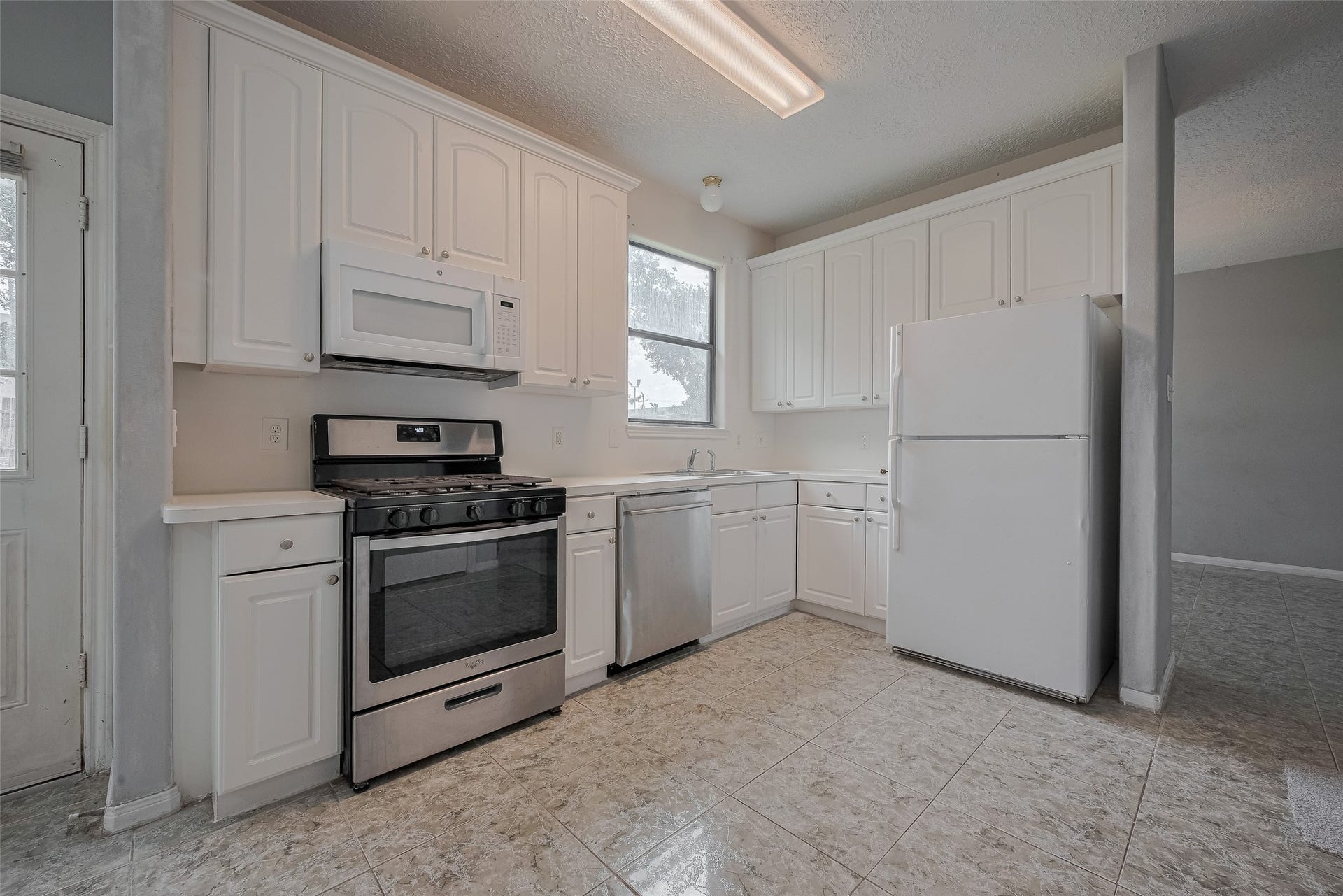 11214 Palmsprings Drive, Houston, TX 77034 Kitchen features white cabinetry, a gas range, an over-the-range microwave, a dishwasher, and a window above the sink.