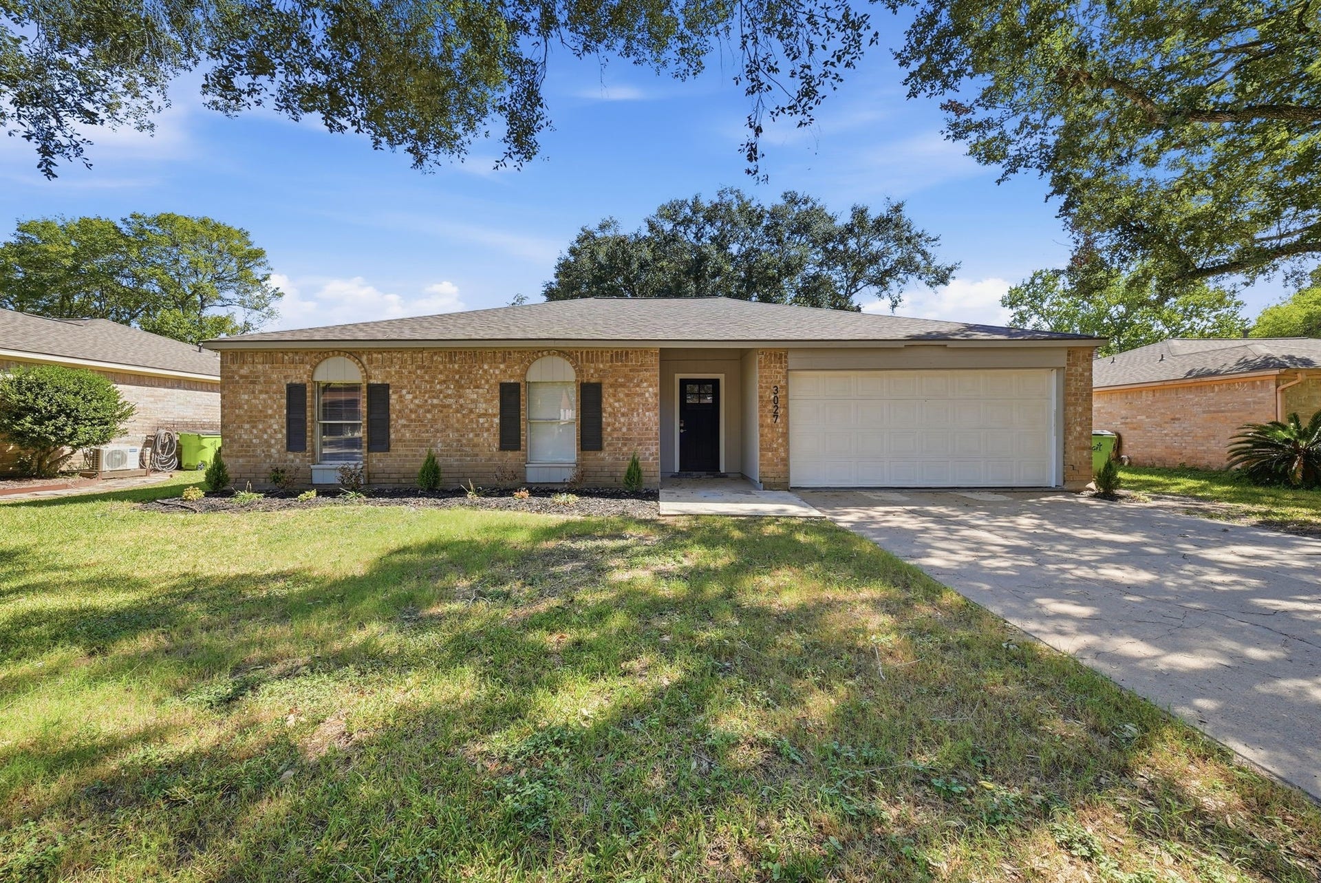 3027 Longhorn Drive, Rosenberg, TX 77471 Brick single-story home under mature oaks with a wide driveway and attached two-car garage.