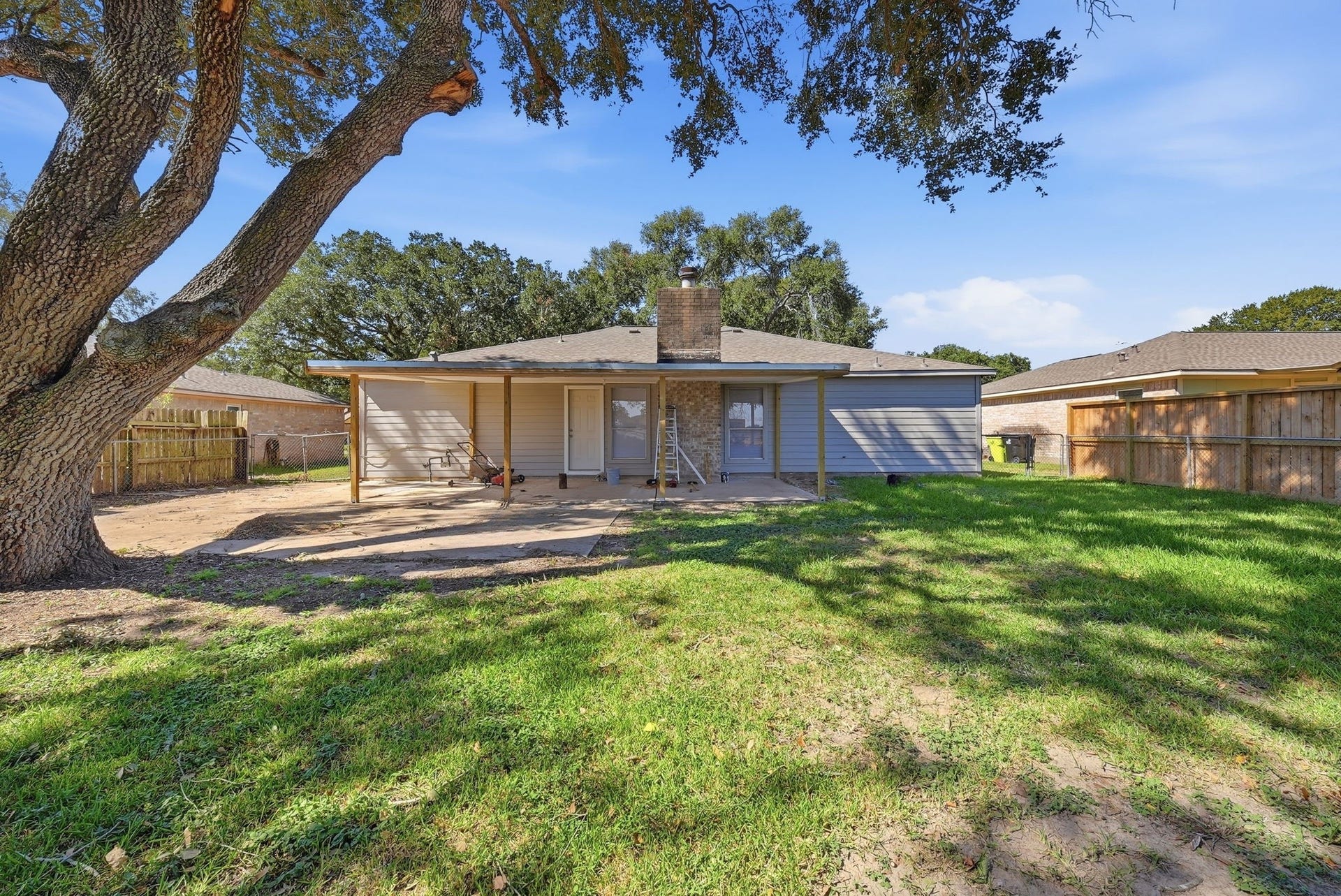 3027 Longhorn Drive, Rosenberg, TX 77471 Fenced backyard with a covered patio, a brick chimney and plenty of lawn.