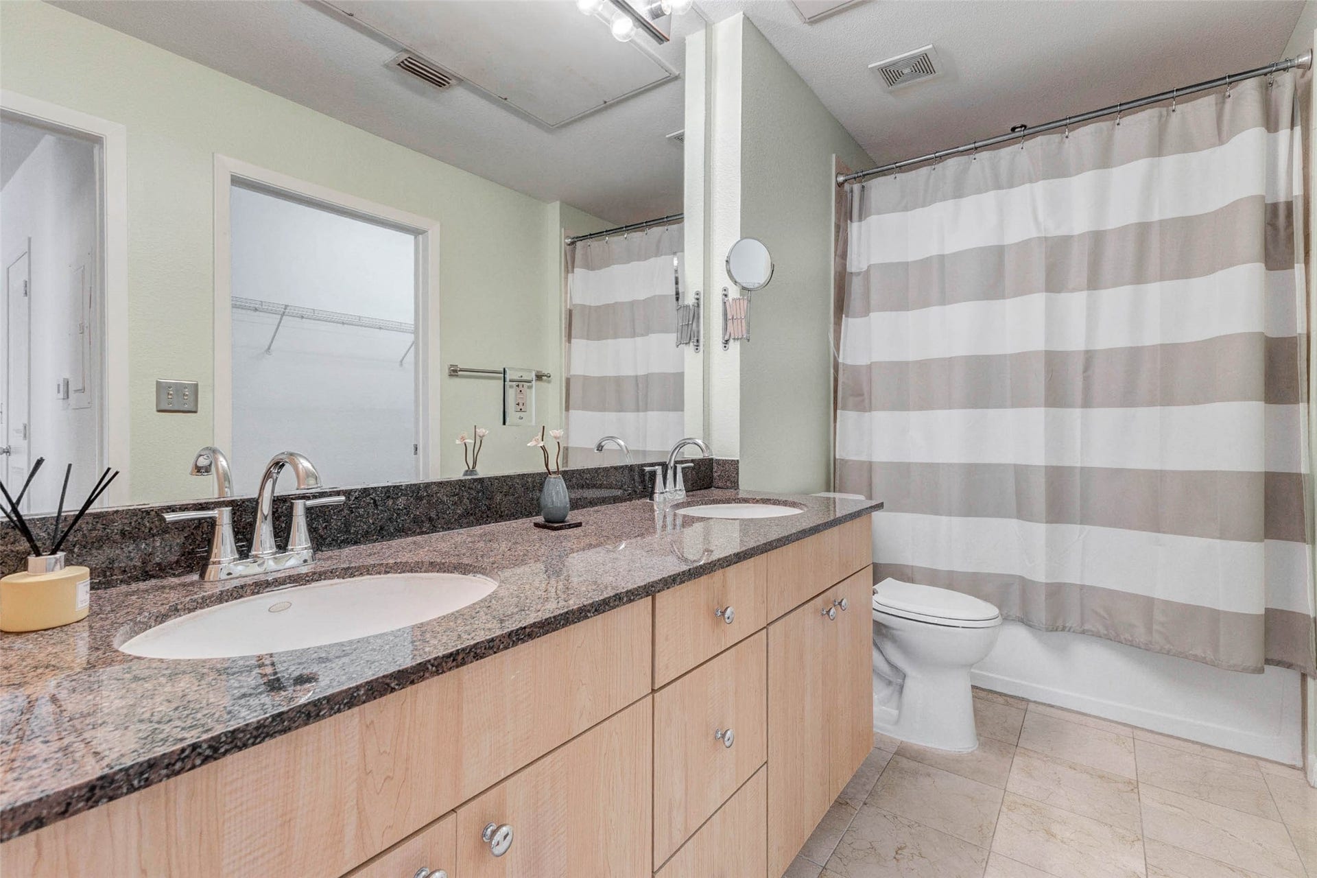 3505 Sage Road, #1104, Houston, TX 77056 The bathroom features a spacious double vanity with elegant granite countertops and ample cabinet storage below. Two sinks provide convenience and functionality, making the space perfect for busy mornings or shared use. The large mirror and bright lighting enhance the rooms openness while reflecting light throughout the space. With clean finishes, modern fixtures, and generous counter space, this bathroom combines comfort and practicality in a well-designed layout.