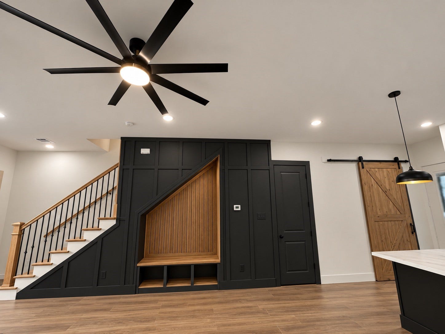 8018 Moon Beam Street, #A/B, Houston, TX 77088 Modern living space featuring a sleek black accent wall with a built in bench, stylish barn door, and elegant staircase with wooden handrails.This photo has been virtually rendered based on the plans for this home.