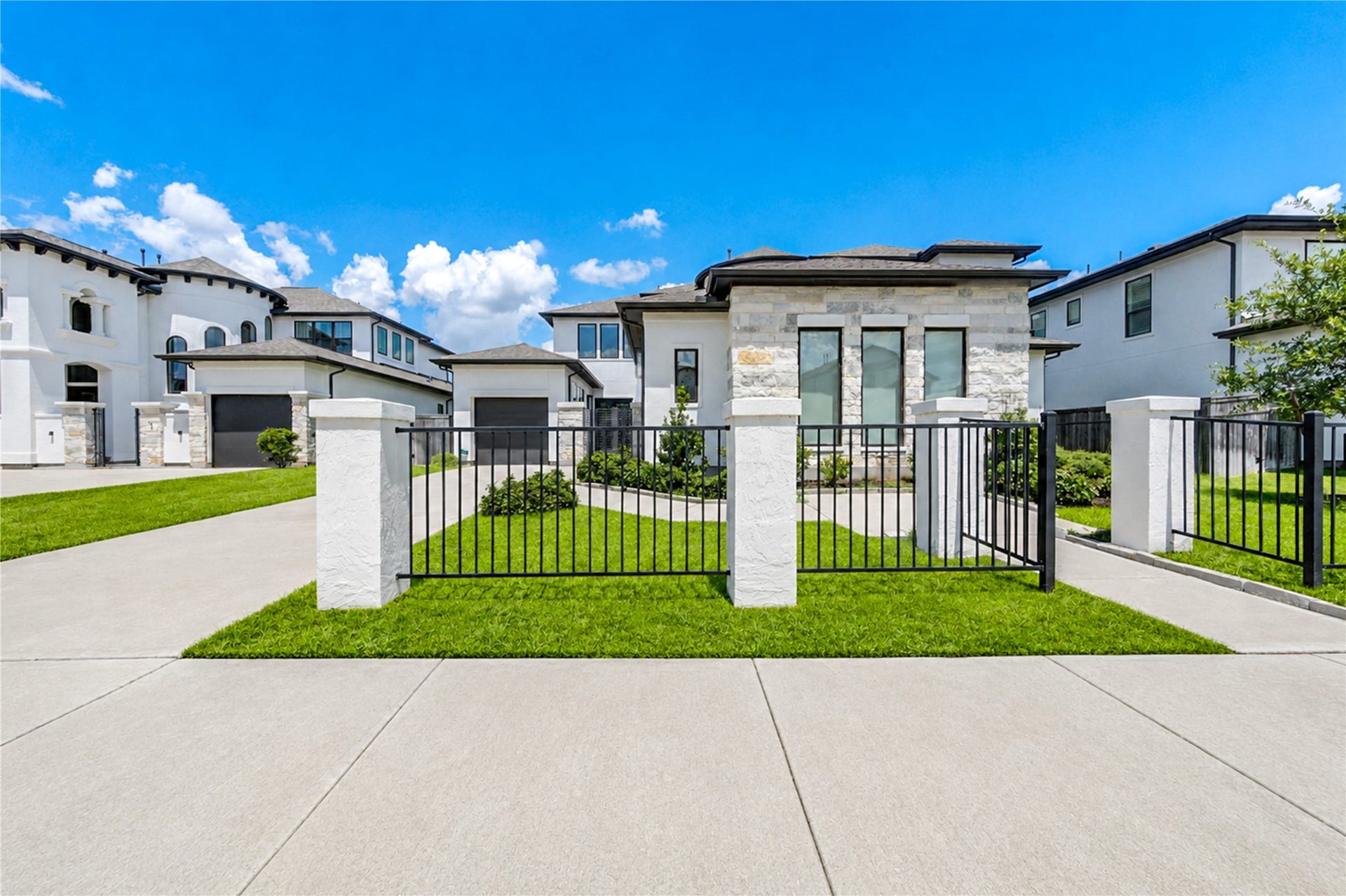 9015 Orchard Cove, Missouri City, TX 77459 Modern two-story home with a sleek stone facade, large windows, and a gated entrance, set in a well-maintained neighborhood.