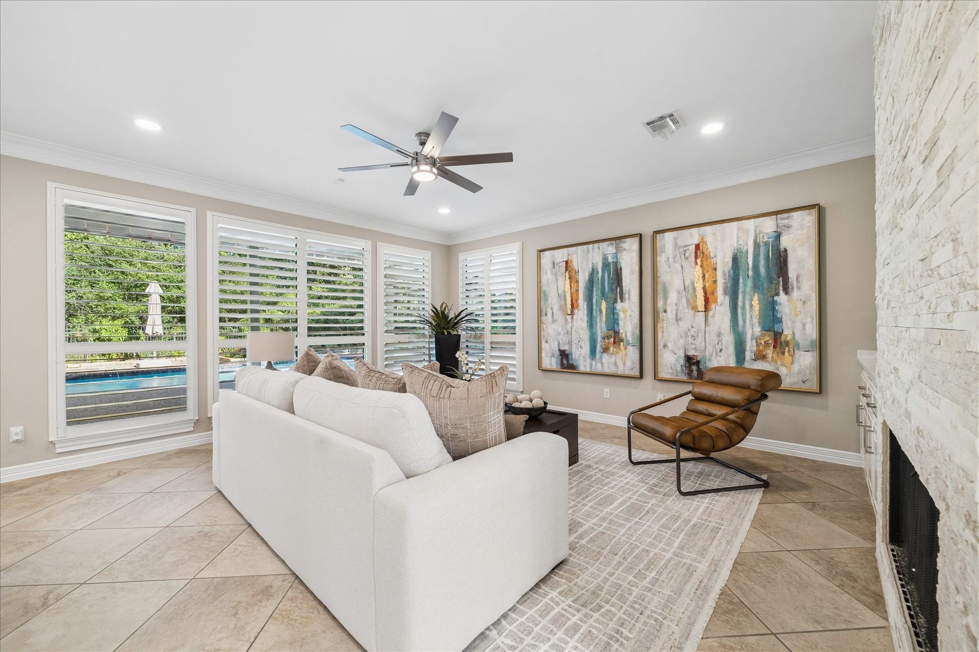 Light-filled living room with expansive windows framing views of the private mature landscape. There are plantation shutters across the house, what a beauty !