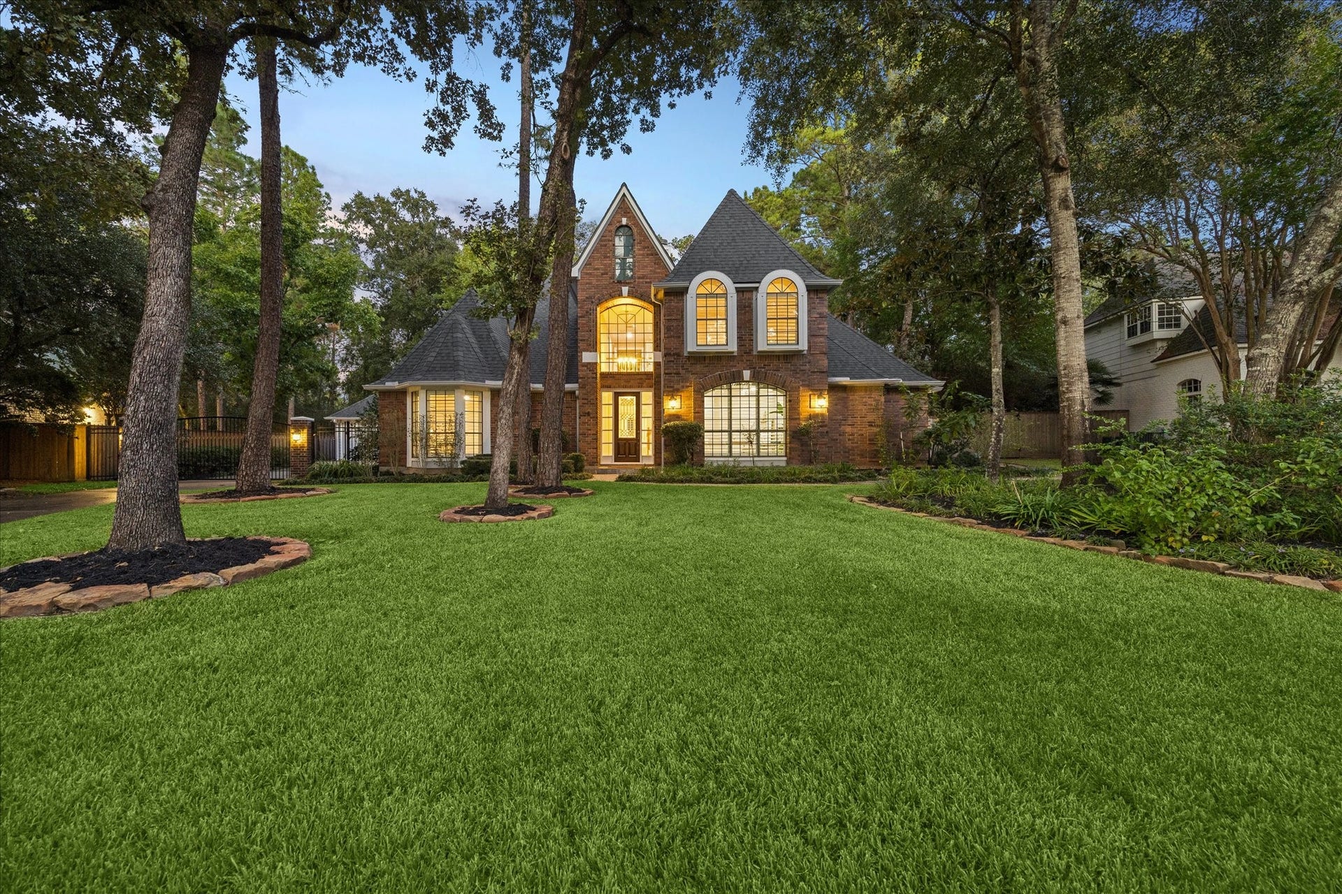 Grand curb appeal beneath a canopy of mature trees, showcasing the home's timeless architecture and exceptional wooded setting.