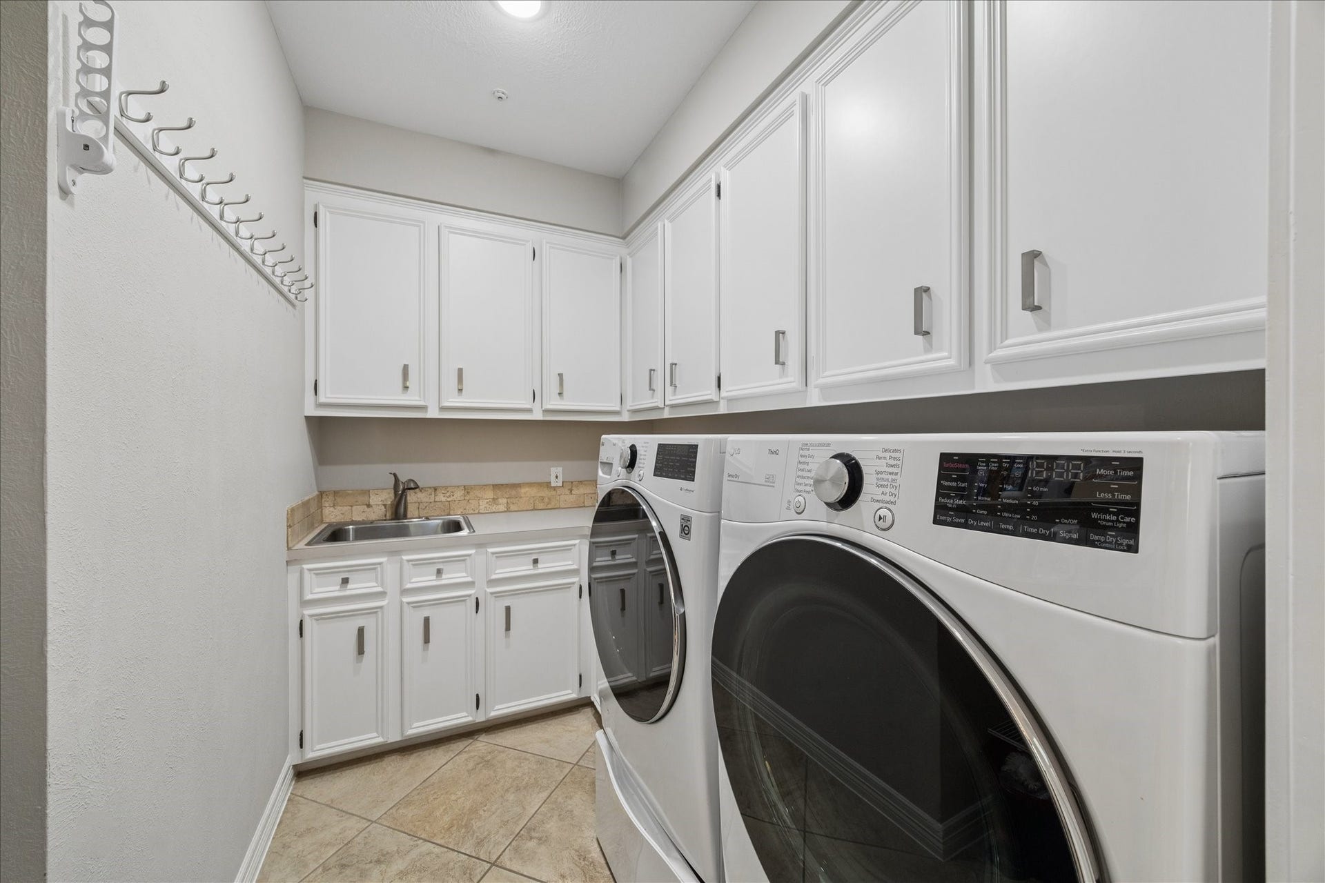 Dedicated laundry room with abundant cabinetry and workspace. With sink and lots of storage. Washer and Dryer stays.