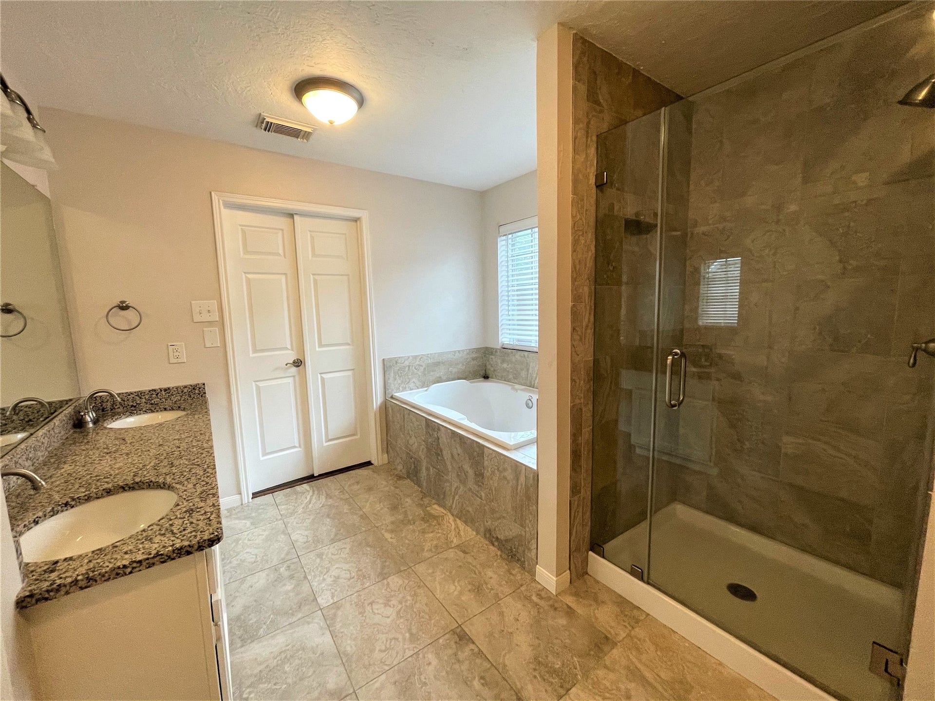 8406 Lake Crystal Drive, Houston, TX 77095 Primary bathroom suite with elongated soaking tub, privacy window, dual sinks and granite countertops.