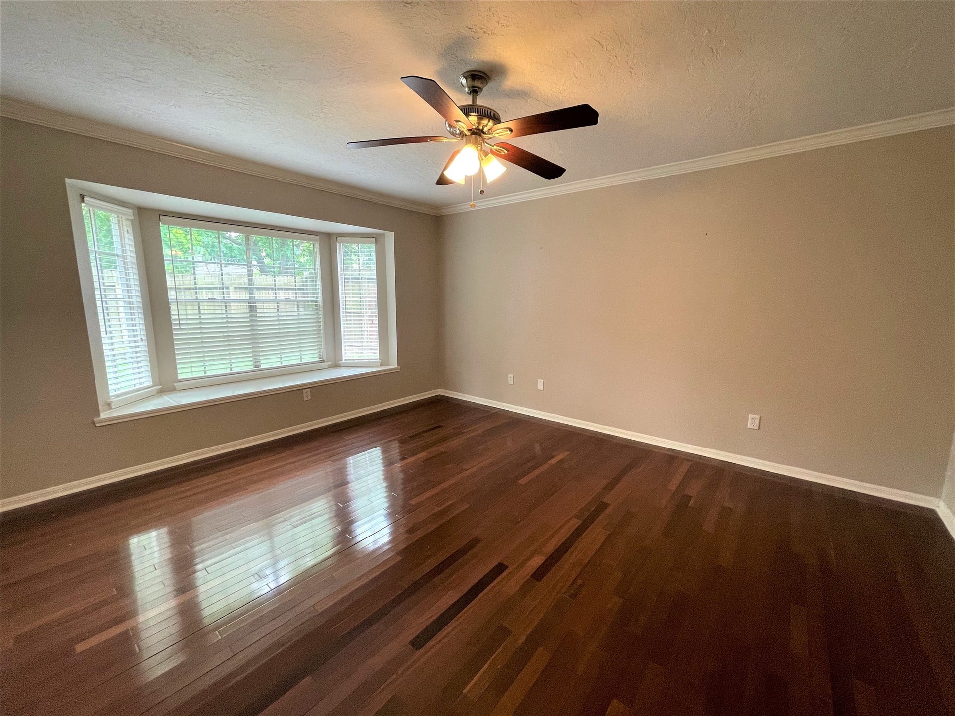 8406 Lake Crystal Drive, Houston, TX 77095 A cozy primary bedroom with elegant hardwood design floors and a stylish ceiling fan, creating a perfect blend of comfort and sophistication.