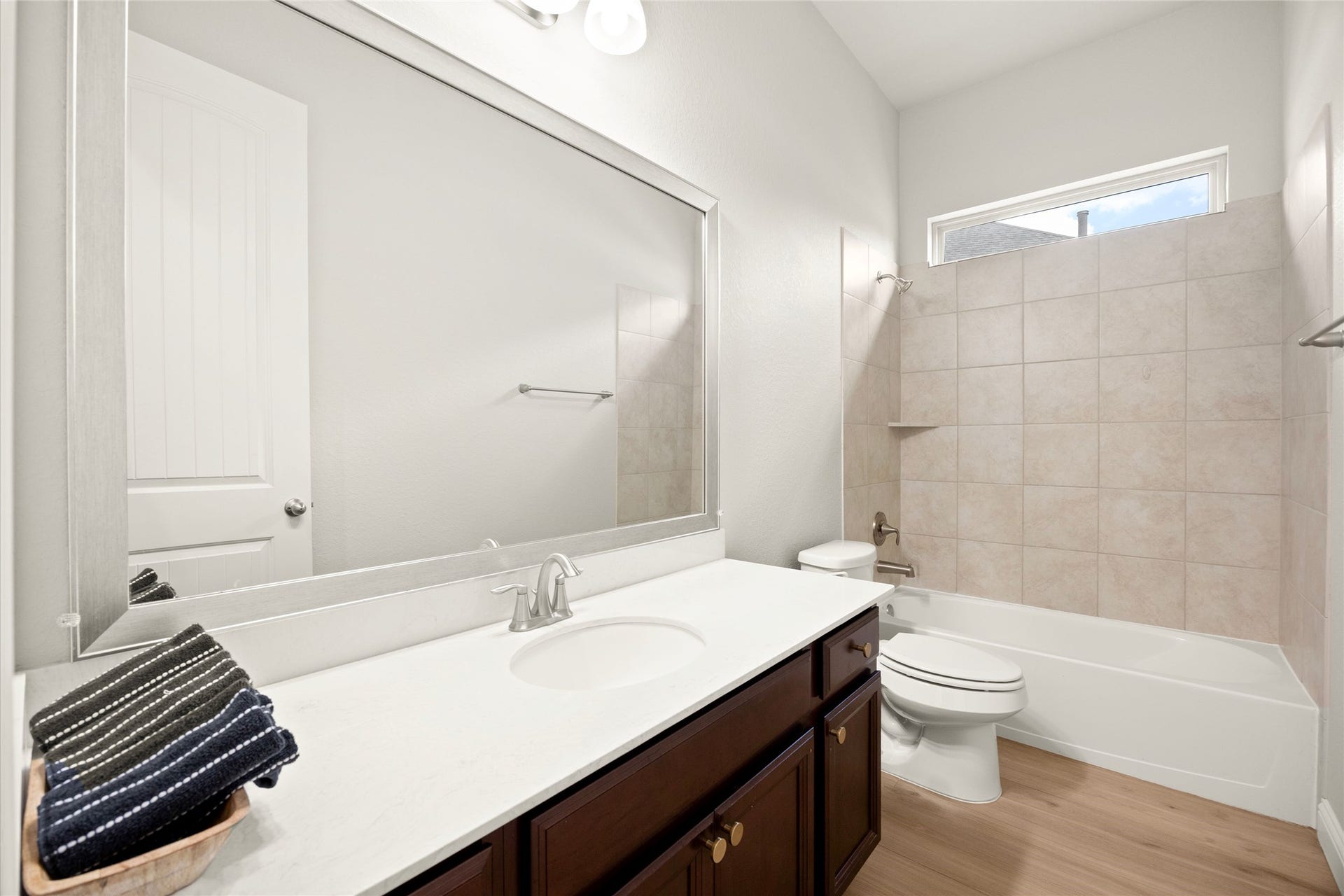 SECONDARY BATH  Bright secondary bathroom featuring an extended vanity, tub/shower combination, and transom window for added natural light.