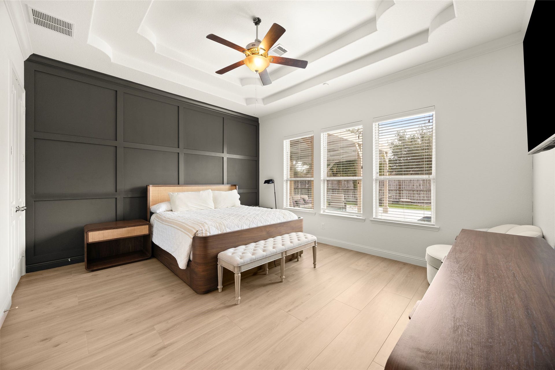 PRIMARY BEDROOM  Spacious primary suite featuring a tray ceiling, custom accent wall, and large windows overlooking the backyard.