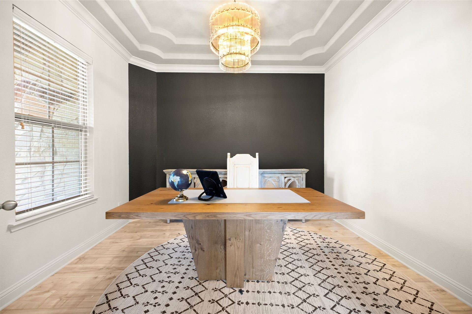 STUDY  Private home office featuring a dramatic tray ceiling, statement chandelier, bold accent wall, and large window offering abundant natural light.
