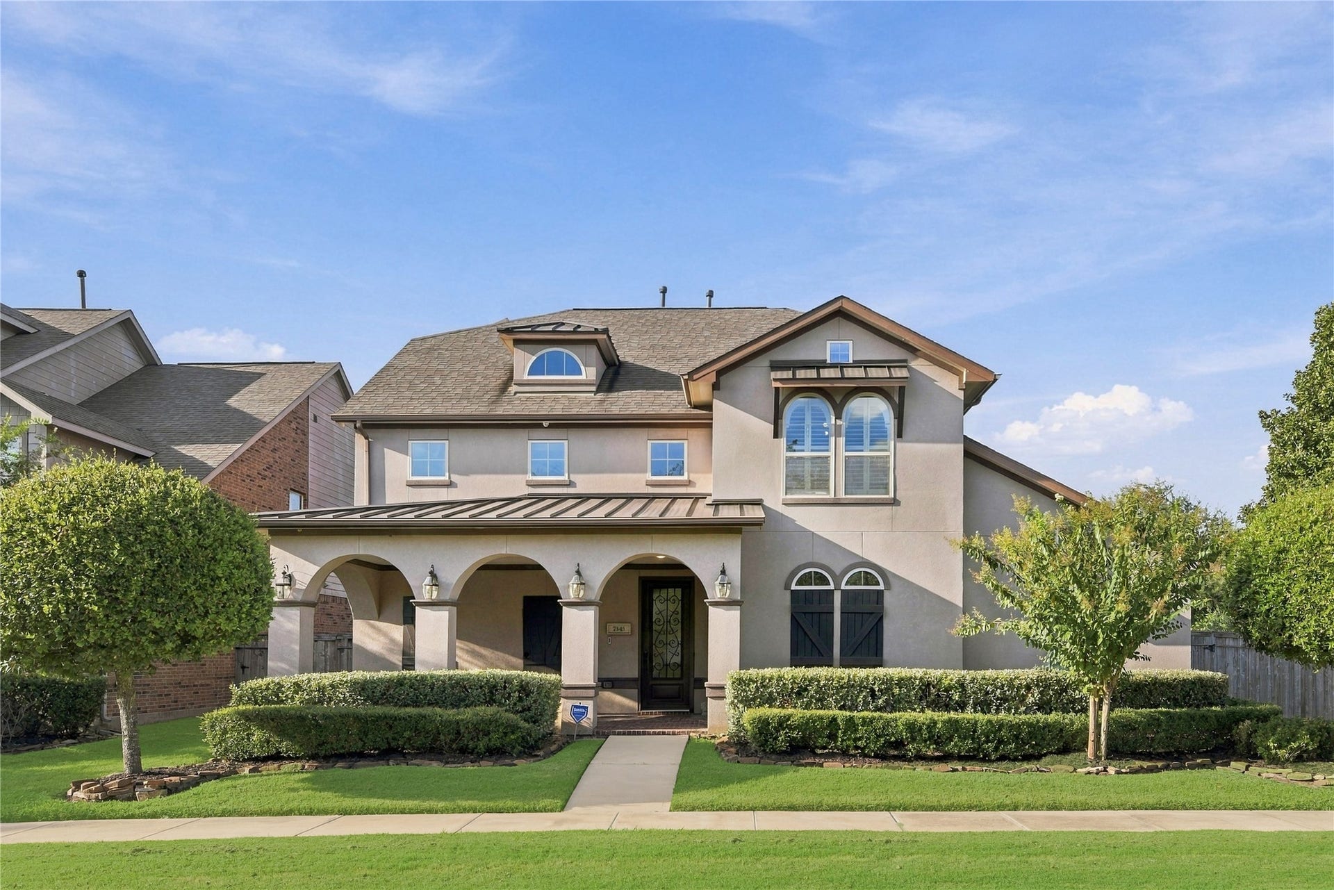 7343 Meadowcroft Boulevard, Sugar Land, TX 77479 Charming two-story home with elegant arched entryway, manicured landscaping, and a welcoming front porch.