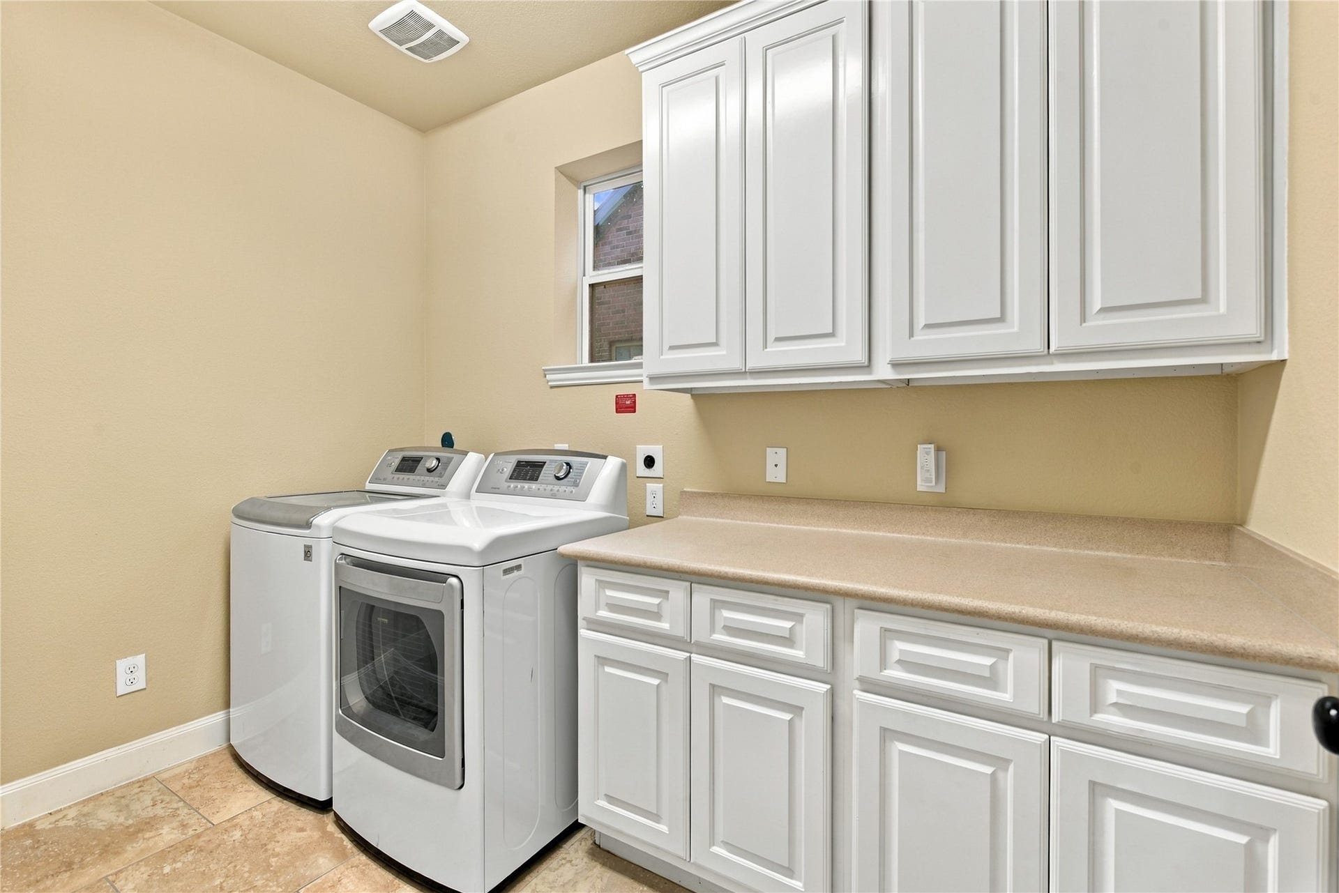 7343 Meadowcroft Boulevard, Sugar Land, TX 77479 Spacious laundry room featuring modern washer and dryer, ample cabinetry for storage, and a convenient countertop for folding laundry.