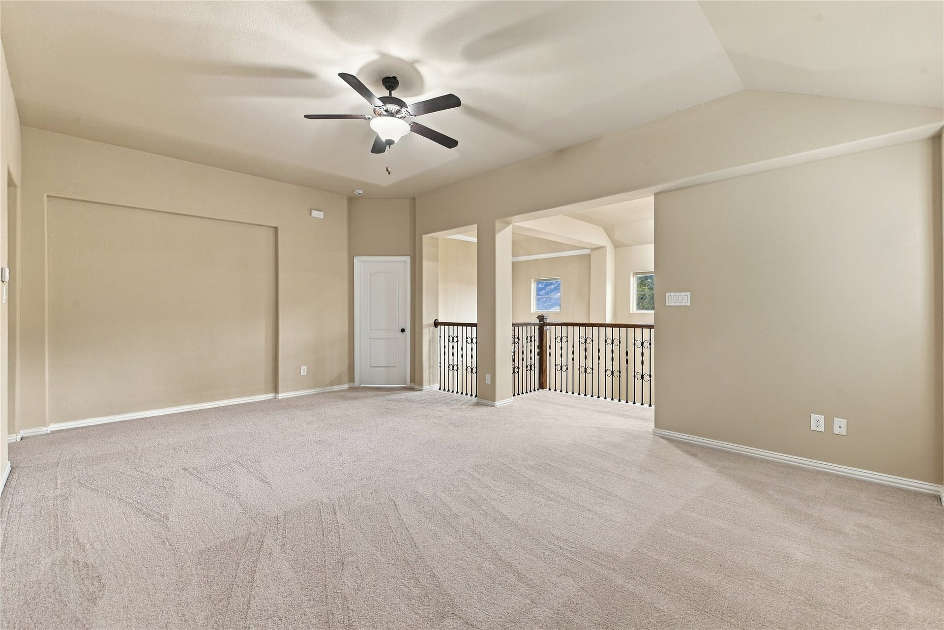 7343 Meadowcroft Boulevard, Sugar Land, TX 77479 This cozy living area features plush carpeting, a ceiling fan for comfort, and an elegant wrought-iron railing overlooking the lower level.