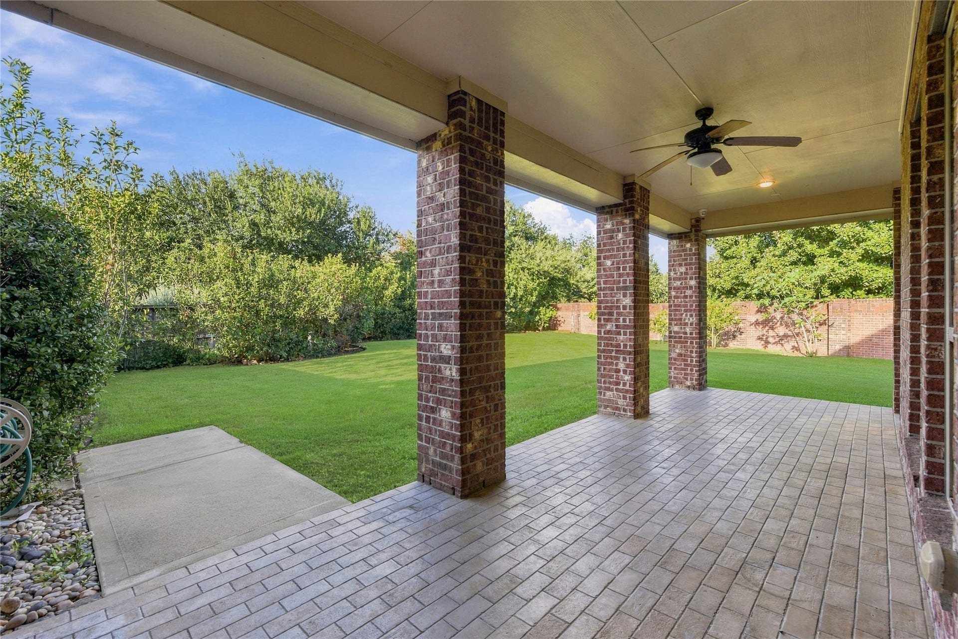 7343 Meadowcroft Boulevard, Sugar Land, TX 77479 Covered patio with ceiling fan overlooking a lush, private backyard, perfect for outdoor relaxation and entertaining.
