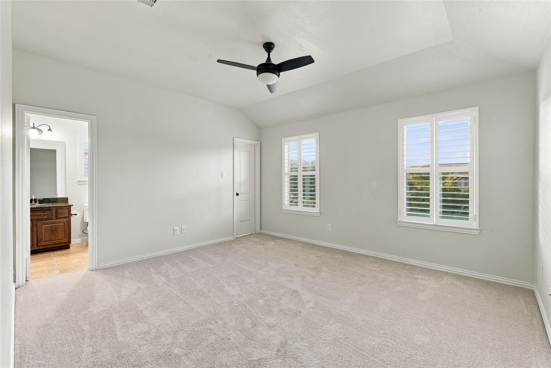 7343 Meadowcroft Boulevard, Sugar Land, TX 77479 3rd Bedroom with plush carpet, abundant natural light from dual windows, and a modern ceiling fan, connecting to a stylish en-suite bathroom.