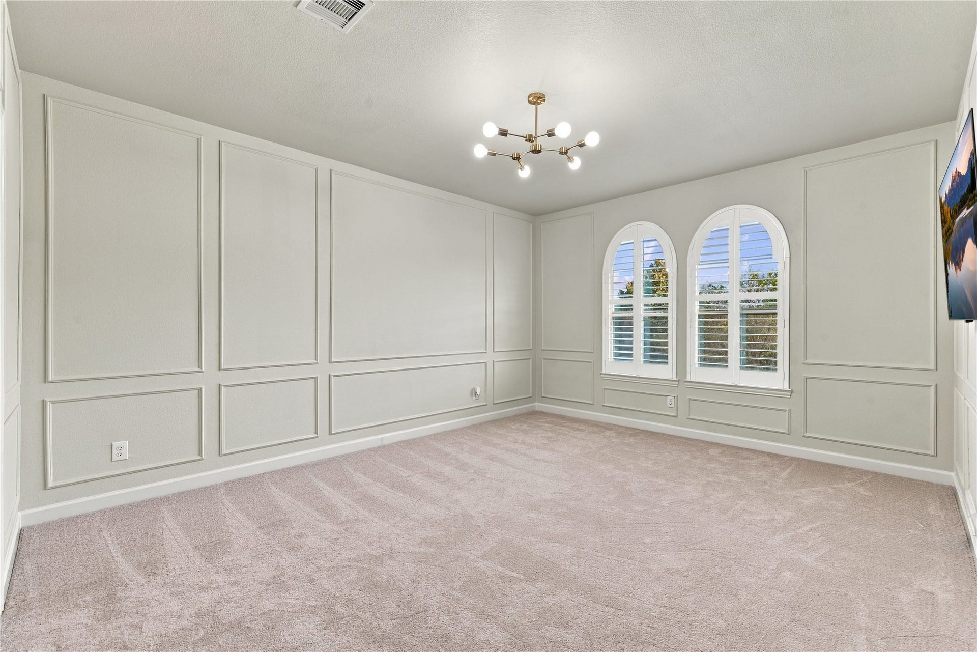 7343 Meadowcroft Boulevard, Sugar Land, TX 77479 Bright and gorgeous room featuring elegant wainscoting, plush carpeting, and arched windows with plantation shutters, complemented by a modern light fixture.