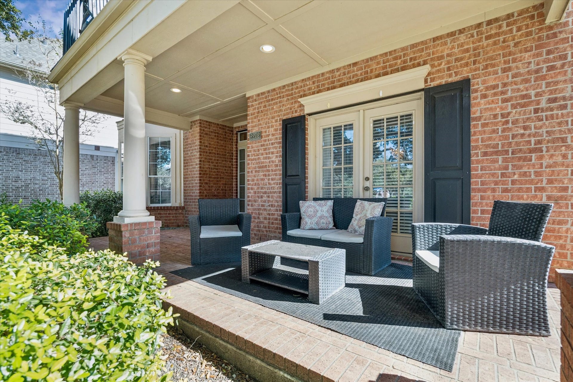 INVITING COVERED FRONT PORCH WITH BRICK DETAILING AND PLENTY OF SPACE TO RELAX OR GREET GUESTS YEAR-ROUND.