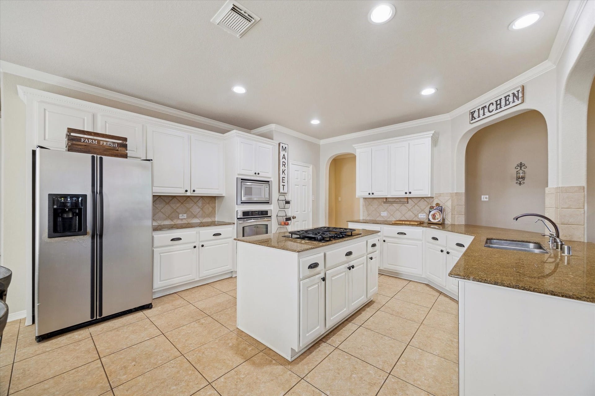 SPACIOUS KITCHEN WITH LARGE CENTER ISLAND, GRANITE COUNTERTOPS, DOUBLE OVENS, AND EXTENSIVE CABINETRY.