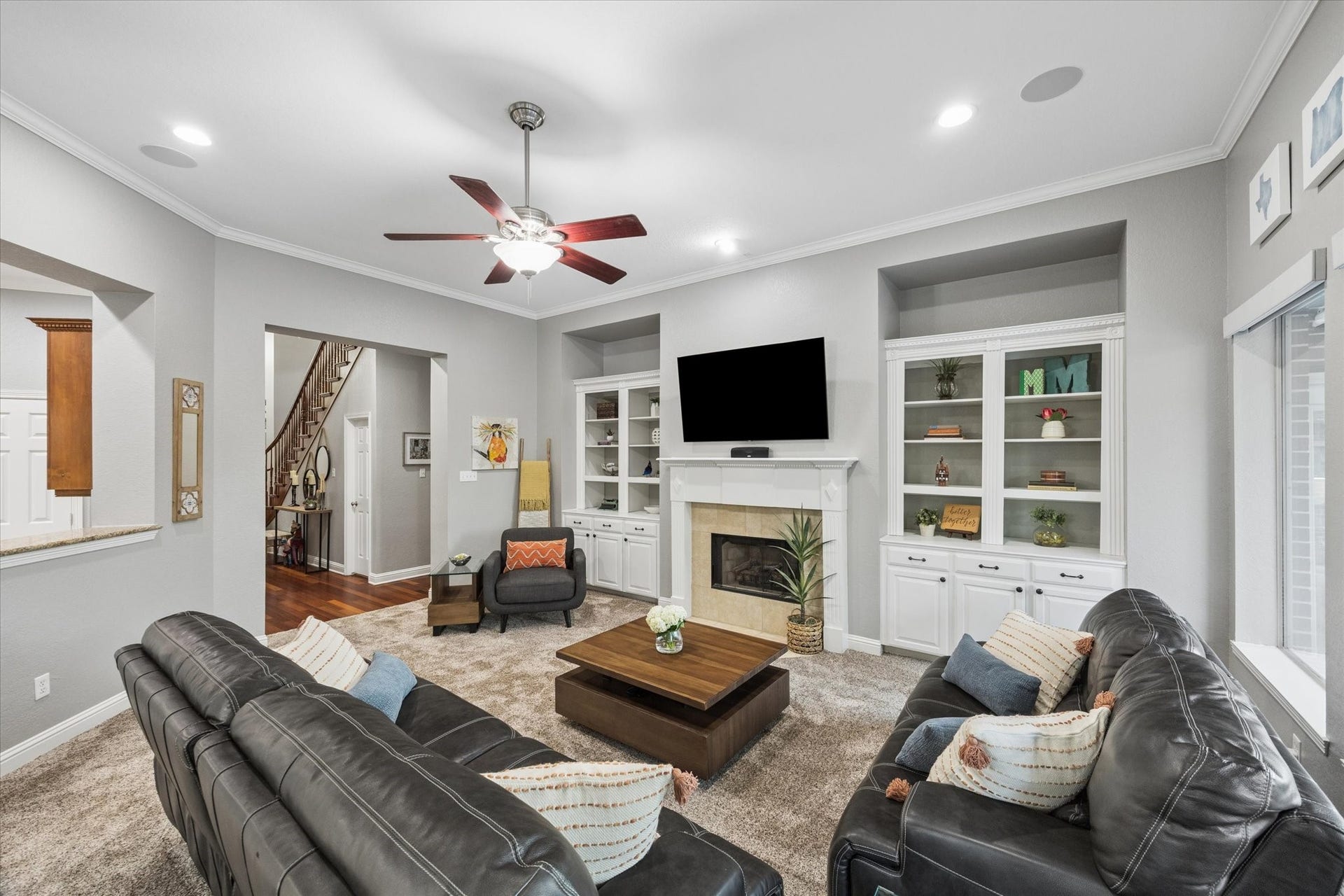 3523 Silvercreek Drive, Manvel, TX 77578 Living room with newly replaced carpet, built-in book shelving and cabinetry, gas log fireplace, breakfast bar open to kitchen, ceiling fan with light and built-in speakers