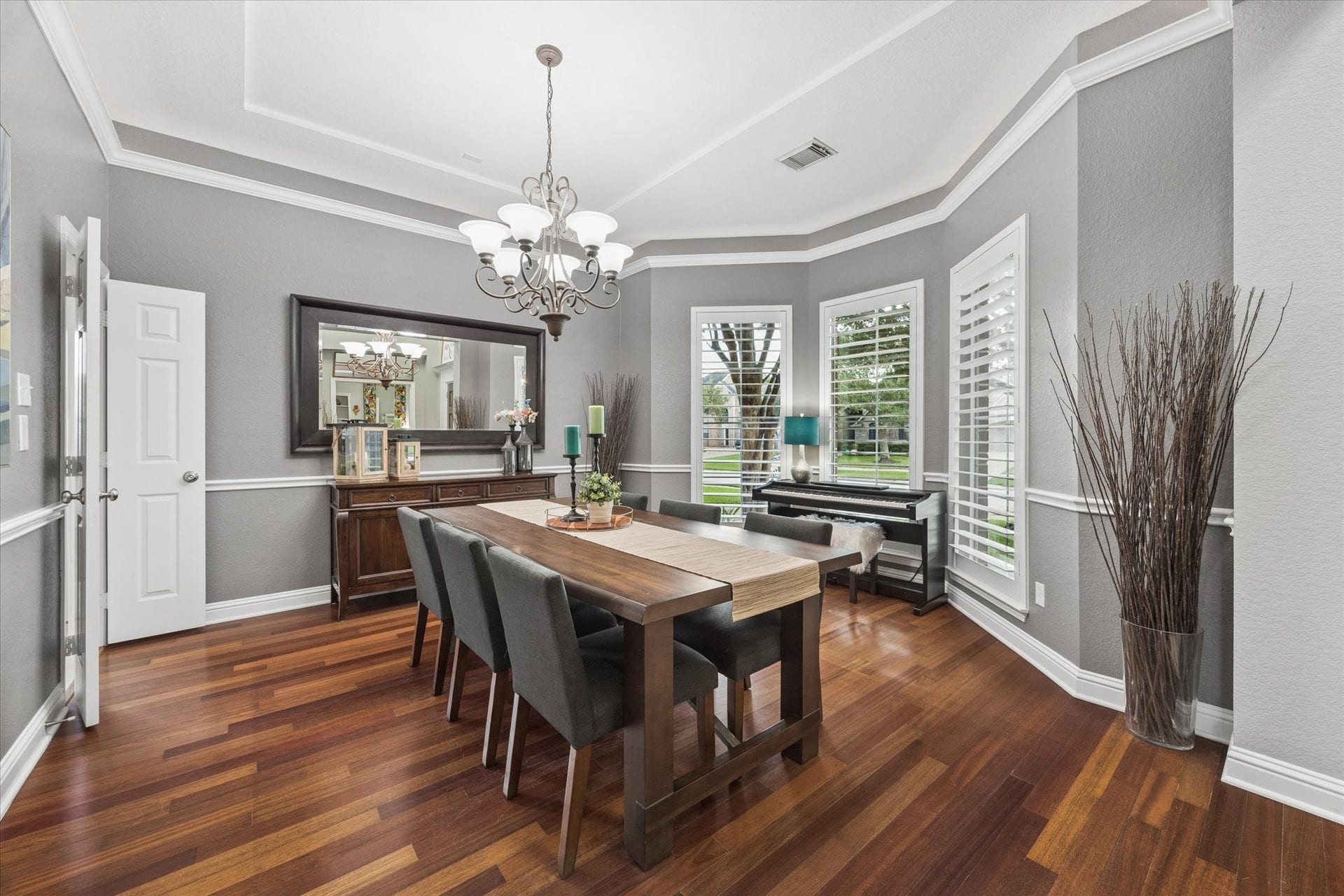 3523 Silvercreek Drive, Manvel, TX 77578 Dining room with views of front yard and mature trees, natural light, plantation shutters, chair railing, hardwood flooring, access door to kitchen for easy serving