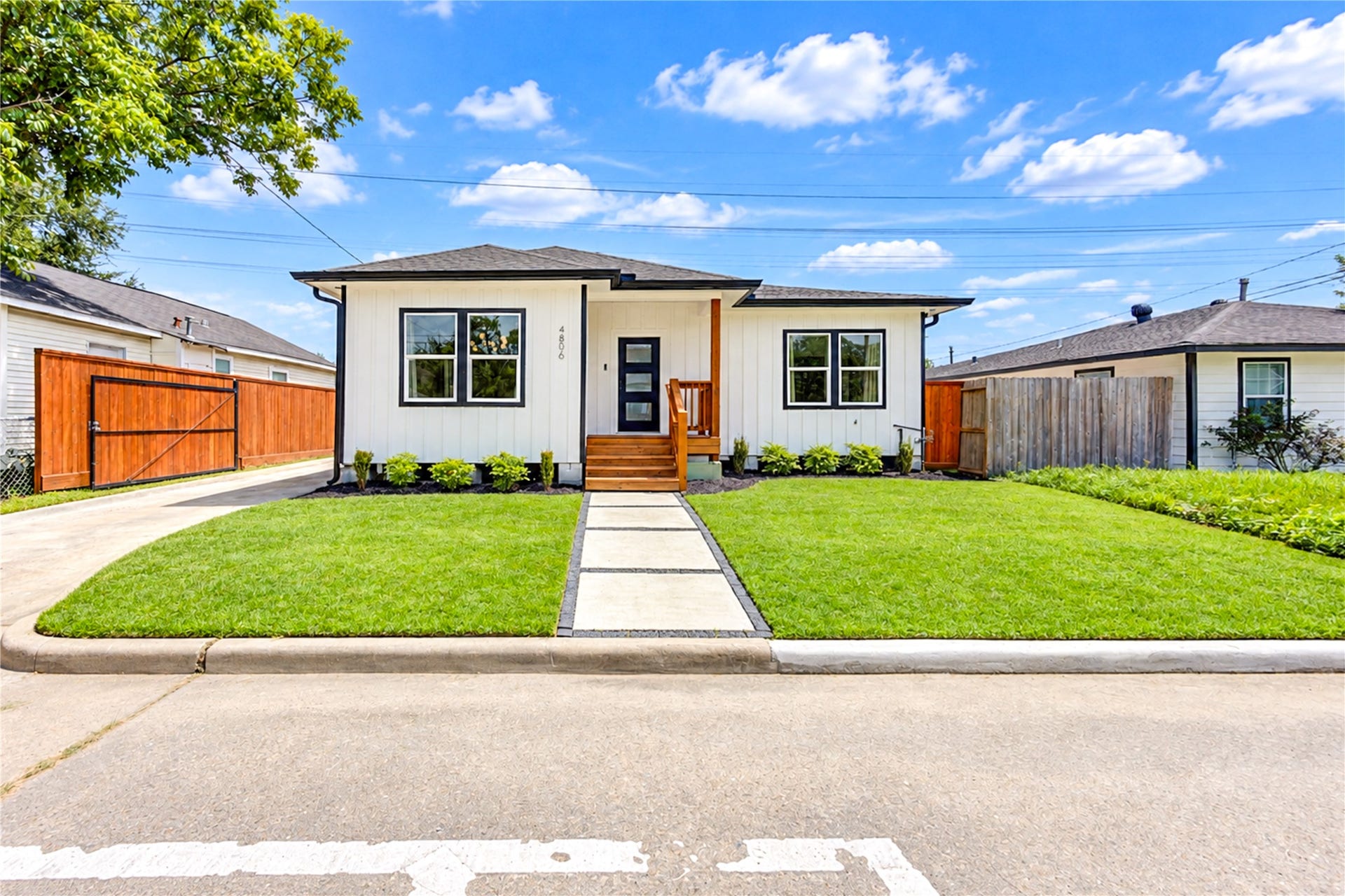 Exterior of home with modern walkway, new sod, driveway gate and beautiful landscaping!