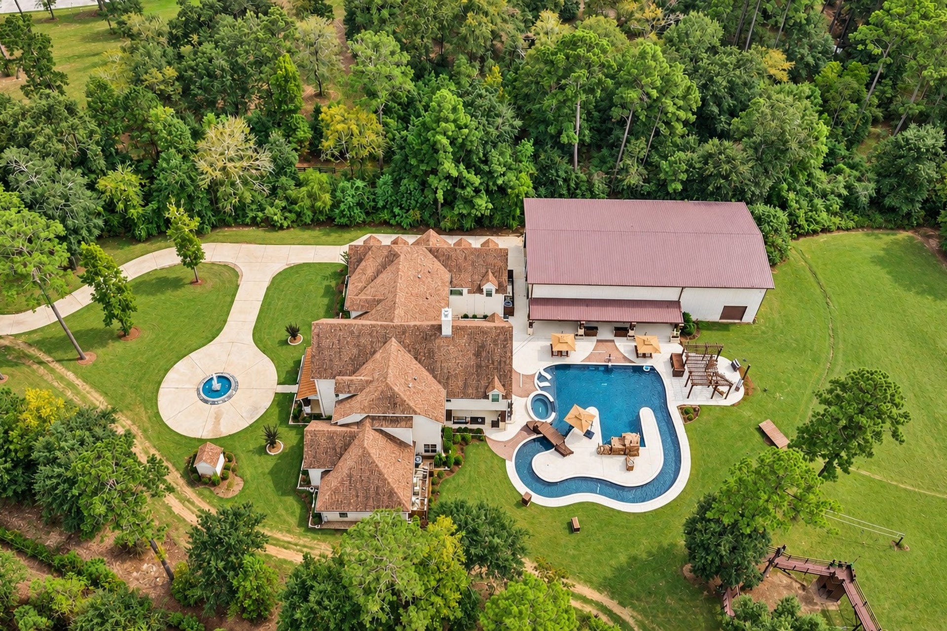 37753 Marias Way, Magnolia, TX 77354 A birds-eye view captures the remarkable scale of the fully fenced estate, from the main residence and resort-style pool to the metal building, outdoor recreation areas and surrounding 10.5 wooded acres.