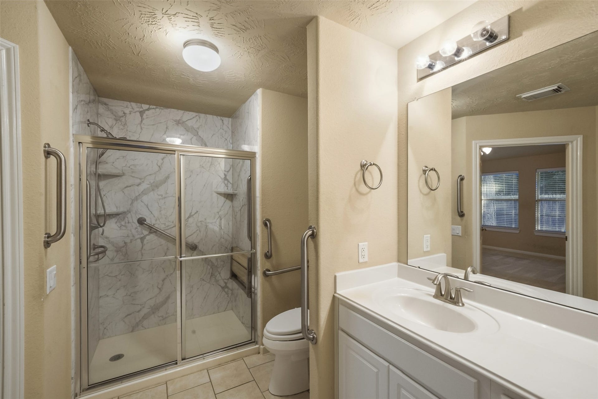 7 Fitzroy Place, Conroe, TX 77384 Primary is equipped with a walk in shower. Notice the grab bars by the entry door, commode and inside the shower. Perfect for anyone who may have mobility issues.