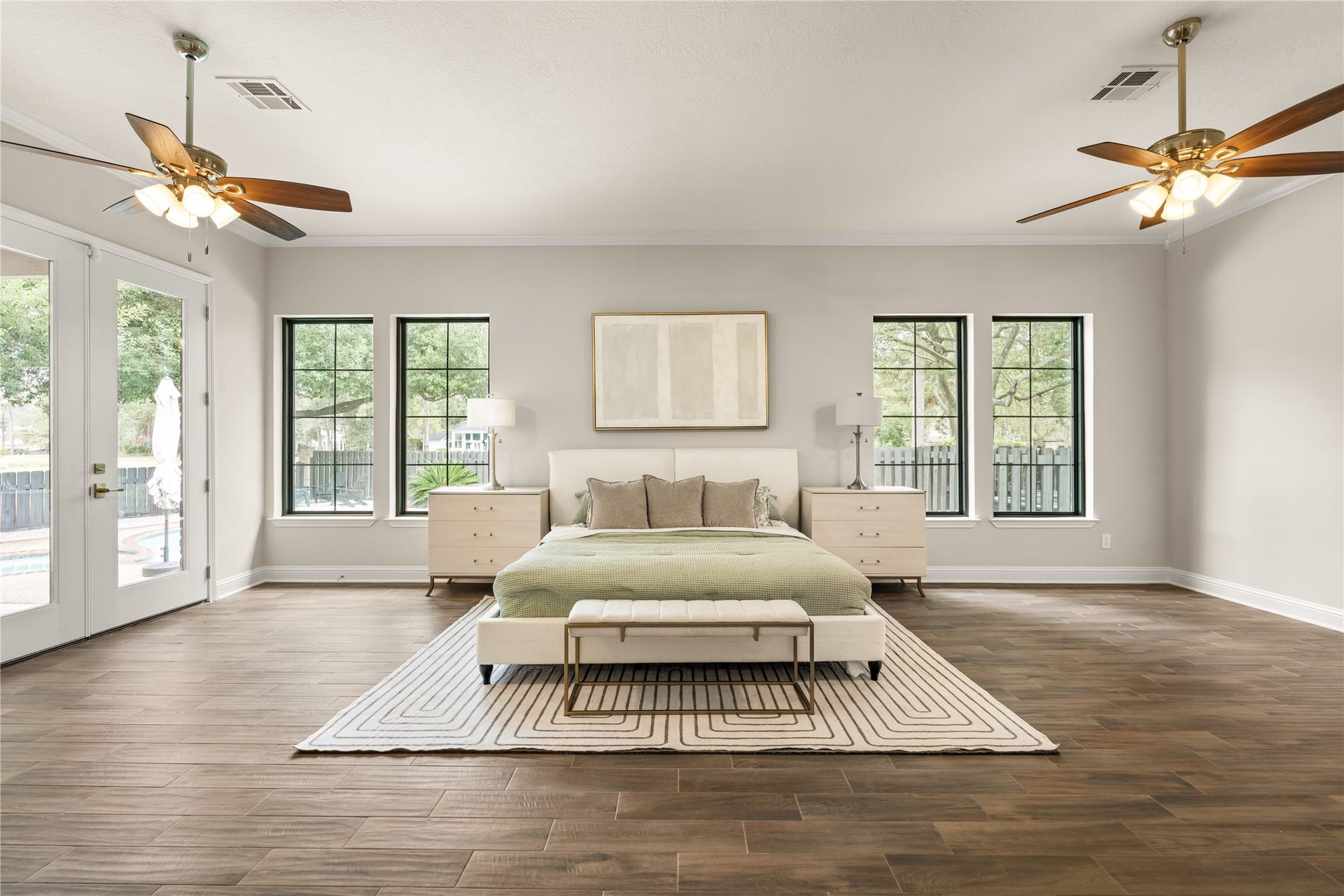 4719 Breezy Point Drive, Houston, TX 77345 An expansive primary retreat filled with natural light, featuring beautiful wood flooring, multiple windows, and convenient access to the outdoor living area.